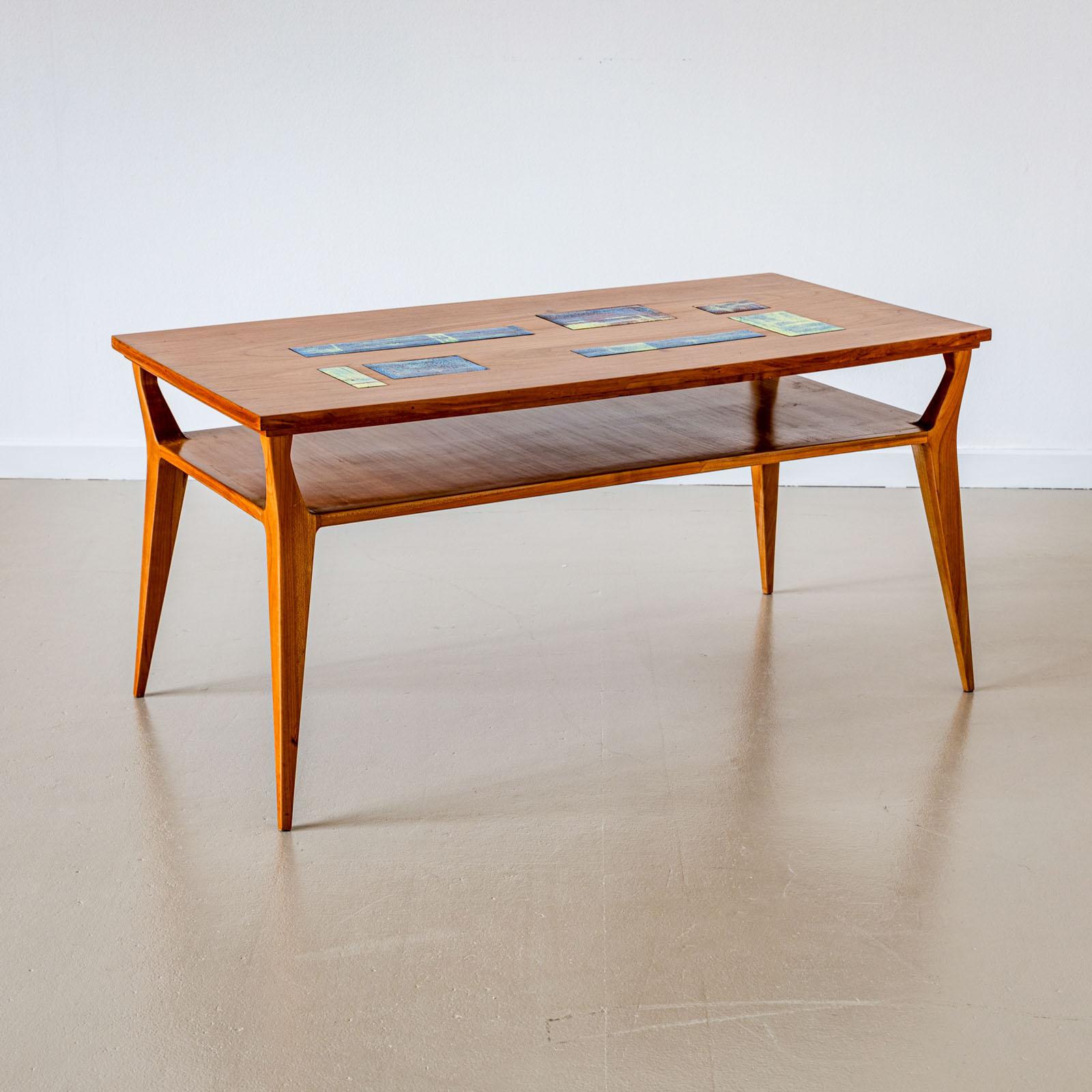 Table basse sur pieds coniques avec plateau rectangulaire. Le plateau de la table est incrusté de disques en céramique émaillée de différentes tailles.