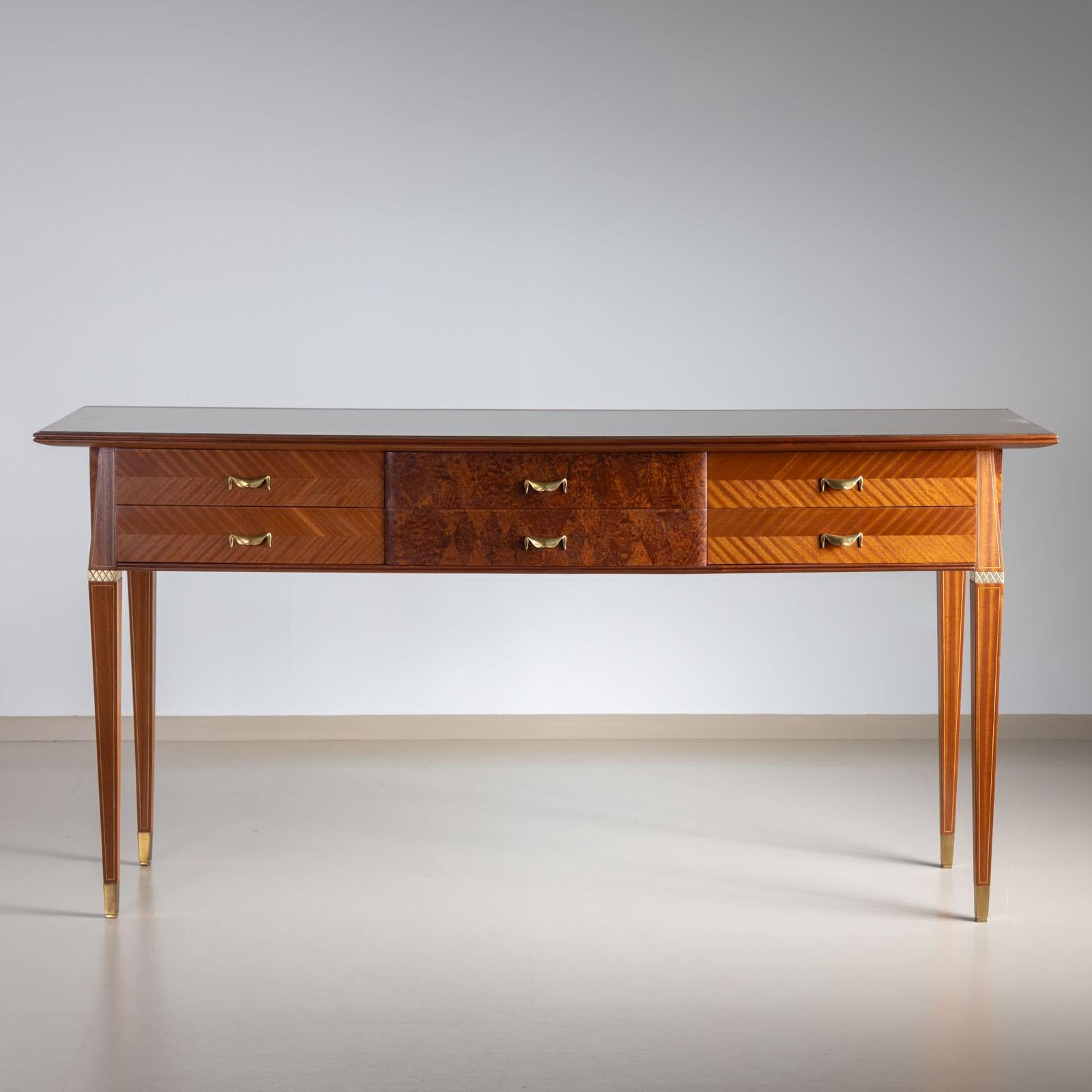 Italian console table on elegant square tapered legs with six drawers and brass sabots. The surface is fitted with an embedded glass panel and backed in gold. The front is decoratively inlaid in herringbone parquetry.