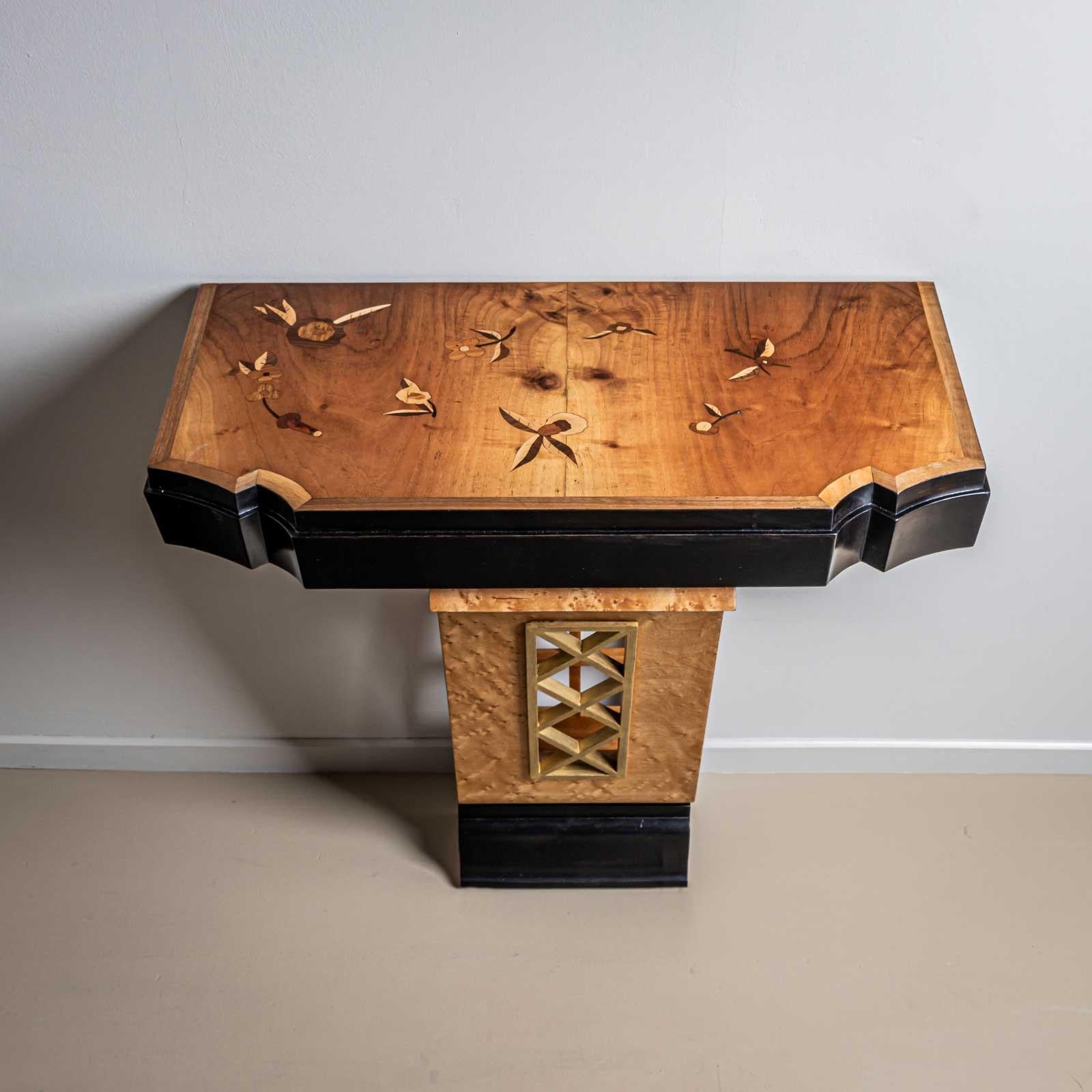 Consola de pared diseñada por Luigi Scremin en la década de 1950. La consola de pared se alza sobre una base estrecha con detalle de celosía calada y base perfilada. El tablero presenta un borde recortado y una superficie incrustada con decoración