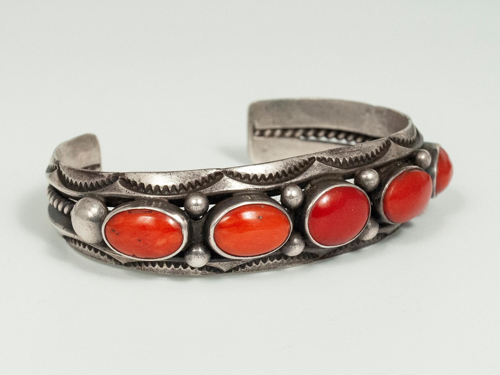 20th century coral and silver bracelet by Fred Thompson, Navajo Jeweler

Five gorgeous cabochons of rich red coral are set in silver bezels, flanked by silver beads and stamped crescents, in this classic bracelet created by master Navajo jeweler,