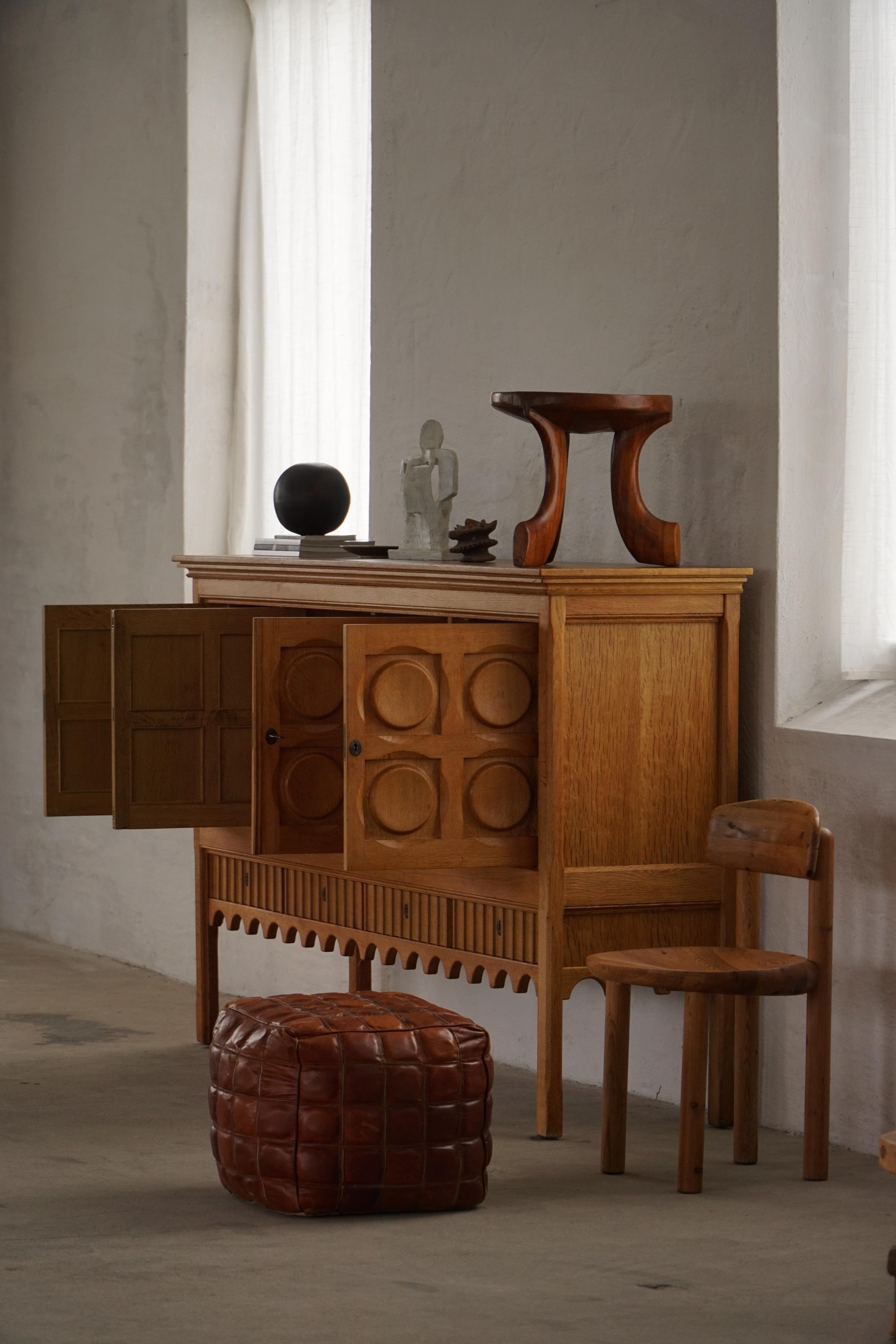 Un'ottomana, un pouf o uno sgabello a forma di cubo rivestito in splendida pelle marrone patinata con un motivo quadrato trapuntato. L'imbottitura garantisce una seduta confortevole, mentre il design geometrico aggiunge un carattere audace e