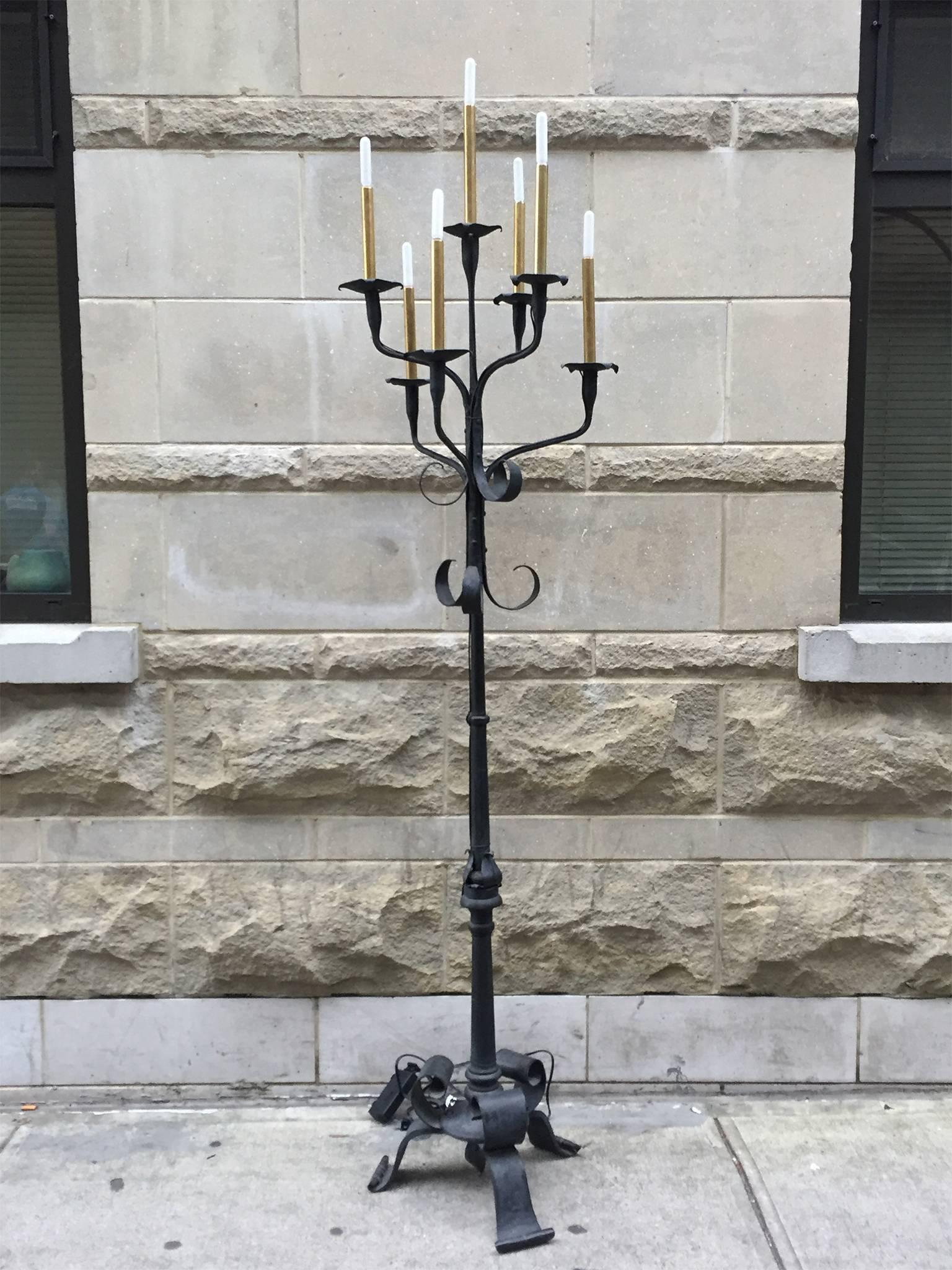 These towering wrought iron torchières were handmade in the 1940s. They have an ebonized coating that lightens the robustness of the iron. Their design is one of whimsy: organic, flat ribbons that end in curlicues. At the top, seven candelabra style
