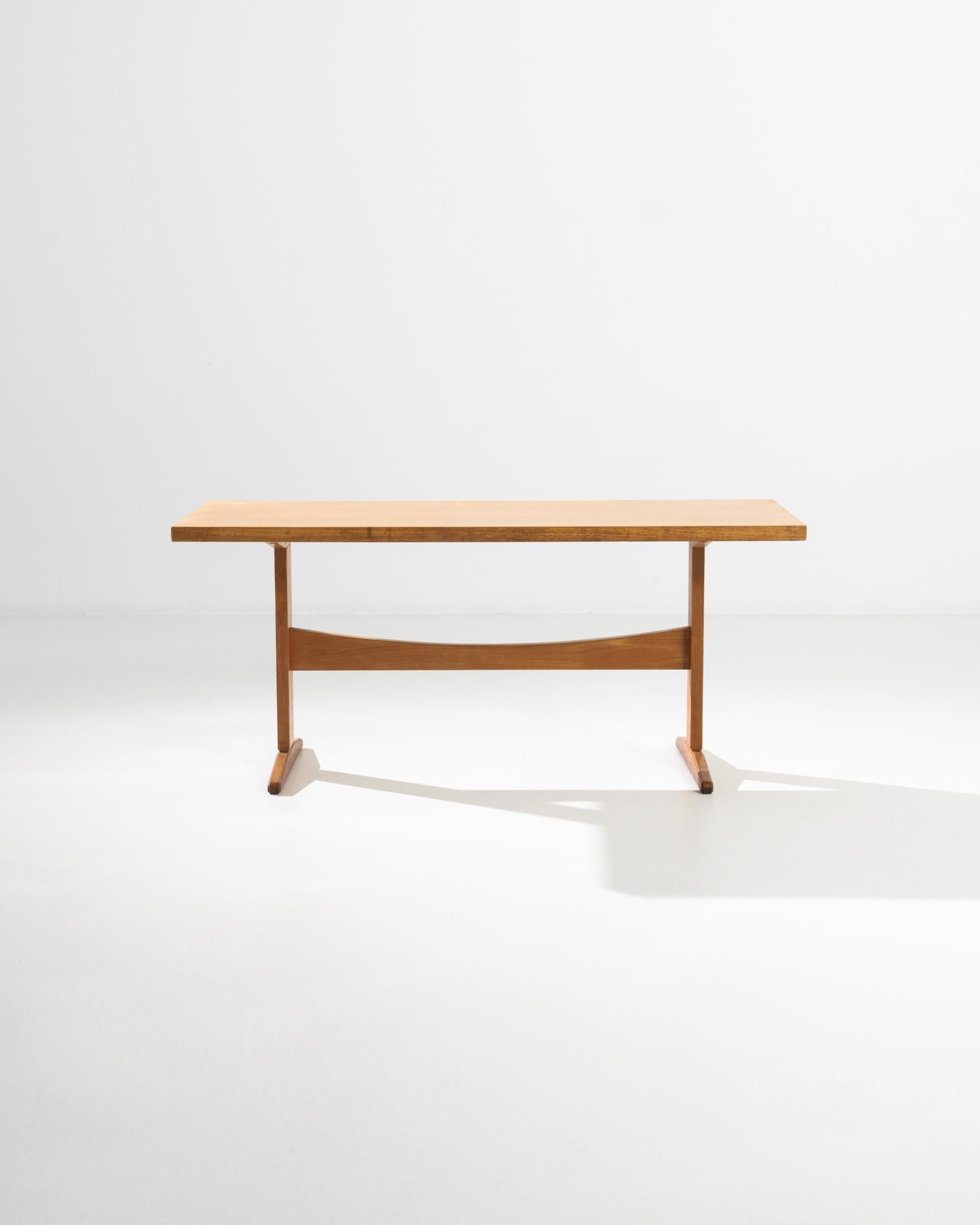 A Mid-Century Modernist twist on the classic trestle table, this vintage piece was built in Czechia in the mid 20th century. Clean lines in bright wood create a bold yet playful design. The curve of the stretcher, gentle yet precise, offers a