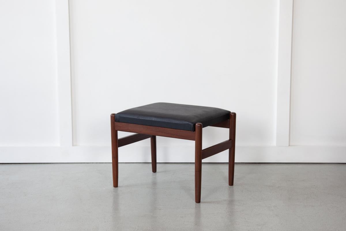 A sweet footstool, designed and manufactured in Denmark in the 1960's by Hugo Frandsen for Spøttrup Stolefabrik. The teak frame is sturdy and the wide cushioned seat is upholstered in original skai leather. 