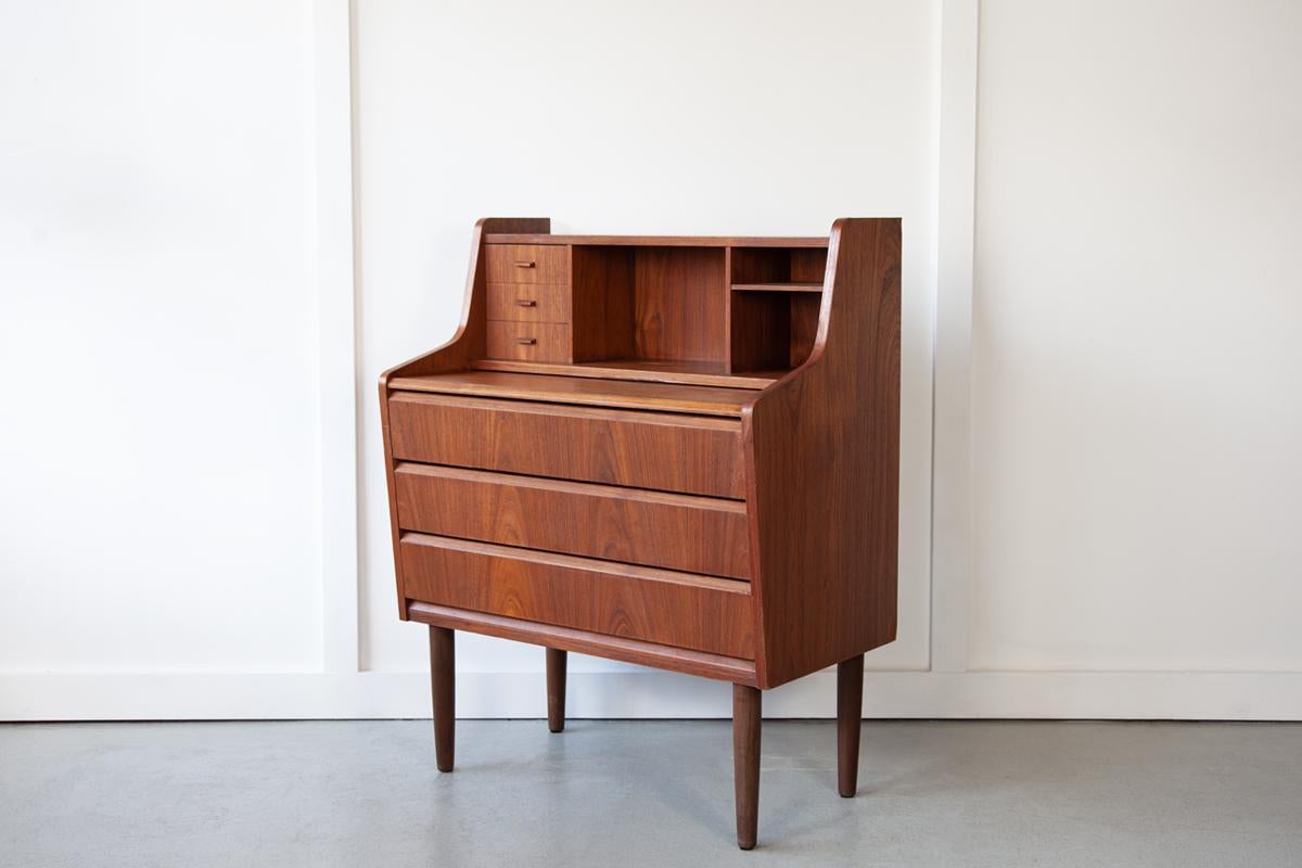 An exquisite and compactly sized teak bureau, produced by Hanbjerg Møbelfabrik in Denmark, with three large and three small drawers, mail slots and a pull out table top, allowing this piece can be used as a writing desk or a lovely dressing table. 