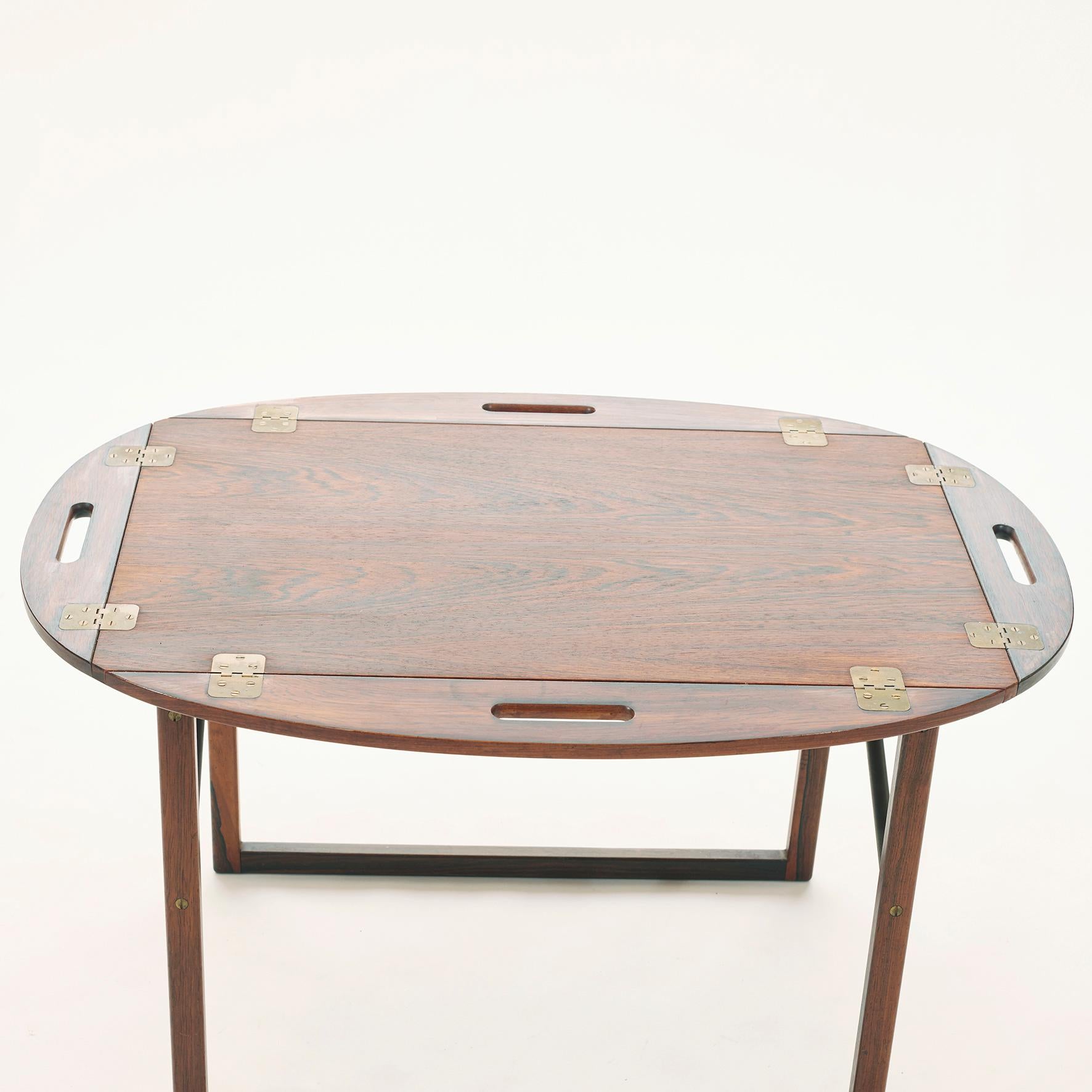 Tray table in rosewood with a removable tray top. Brass hinged edges flip up to convert to handles. 
Danish modern design by Svend Langkilde for Illums Bolighus 1960s.


Dimensions
H 20 in. x W 35 in. x D 24 in.
H 51 cm x W 88 cm x D 61 cm.