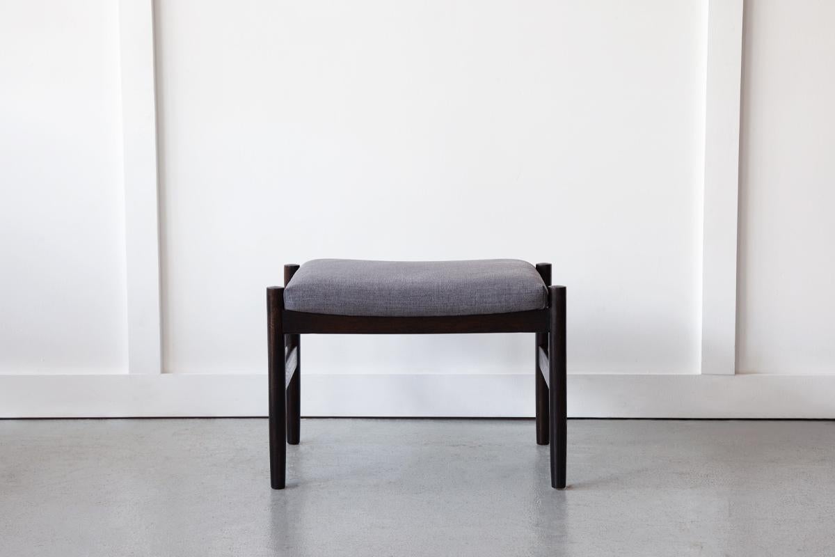 A sweet footstool, designed and manufactured in Denmark in the 1960's by Hugo Frandsen. Newly upholstered in a light charcoal linen.