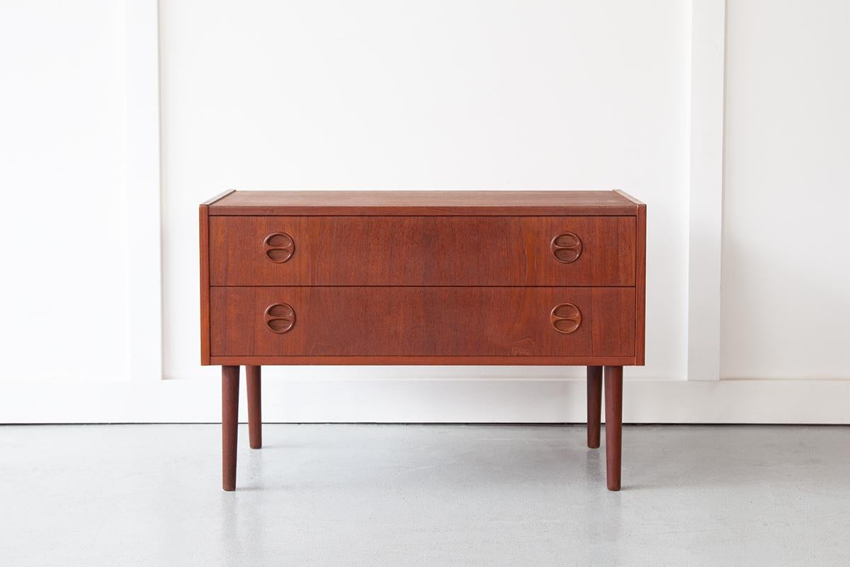 A beautiful low chest of drawers in teak with classically mid century inset handles, ideally sized for use as a TV stand. This piece could also serve as a console in your living room. The simple design is pleasing, characterised by clean lines and