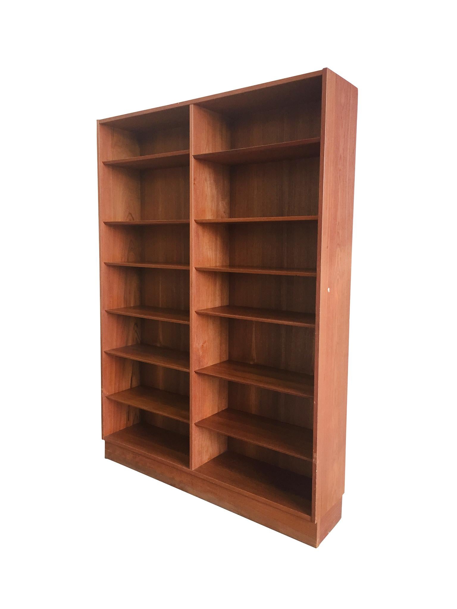 A modern bookcase streamlined into a minimal, elegant form. Designed by Poul Hundevad, mid-20th century. The bookcase is comprised of teak that's patinated in a warm honey-brown tone. The bookcase is crafted exquisitely into two columns of shelves.