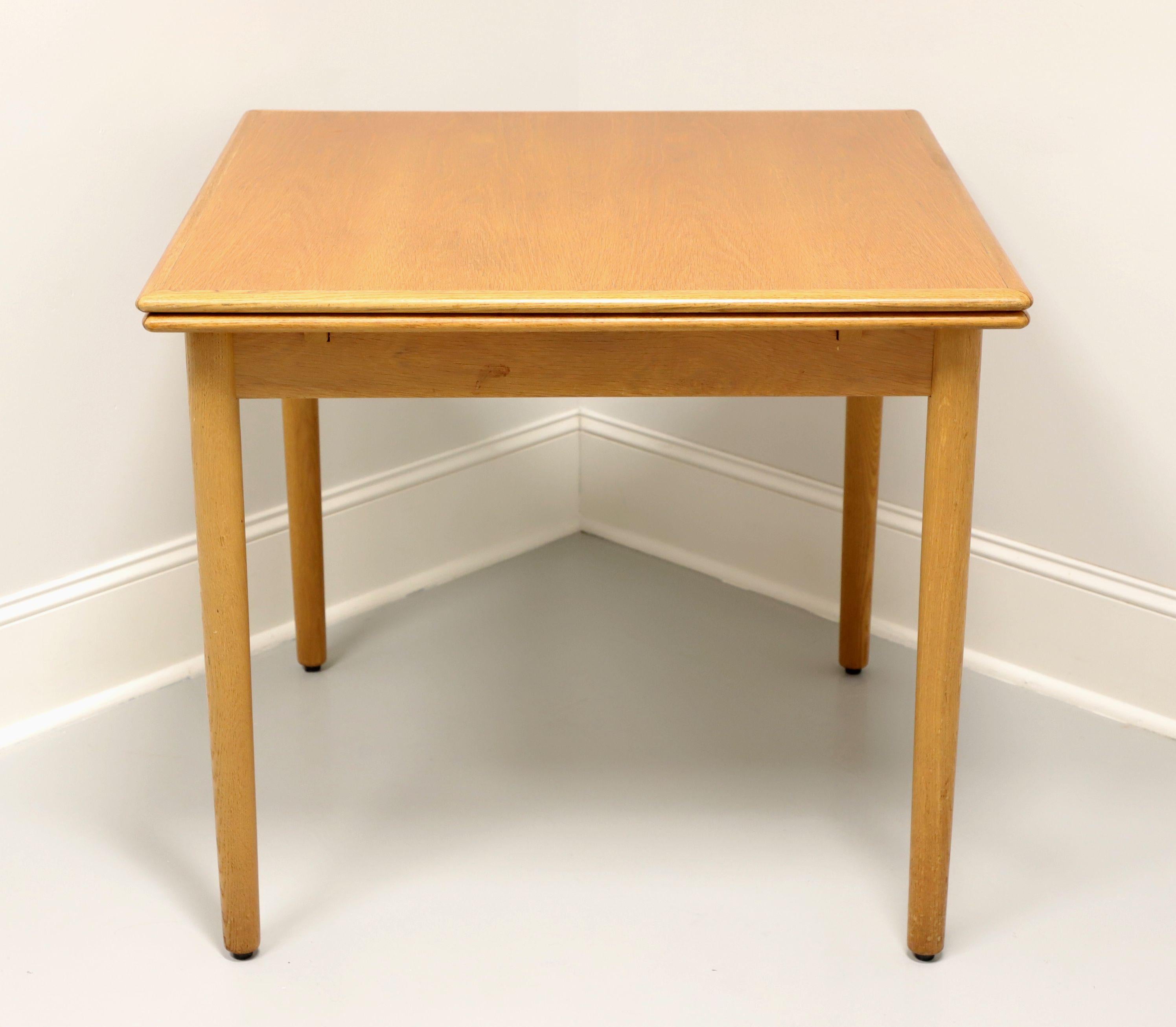 A mid 20th century Danish Modern square drawtop dining table, unbranded. Solid oak with a banded top, two drawtop leaves that pull out from either end of the table by lifting the top, and rounded straight legs. Has two internally stored drawtop