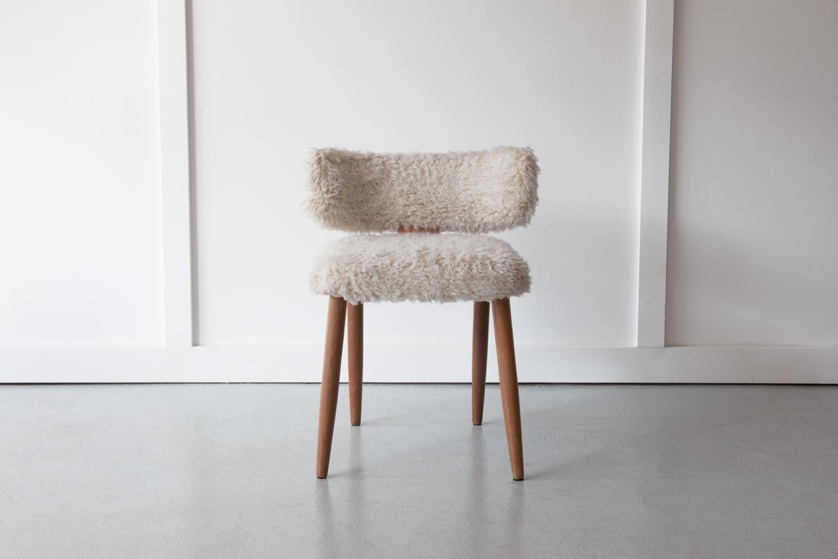 A very sweet Danish side chair or dressing table chair with elegant beech legs and original cream fur upholstery. This chair has a distinct Scandi aesthetic with its enveloping back rest and proud stance.