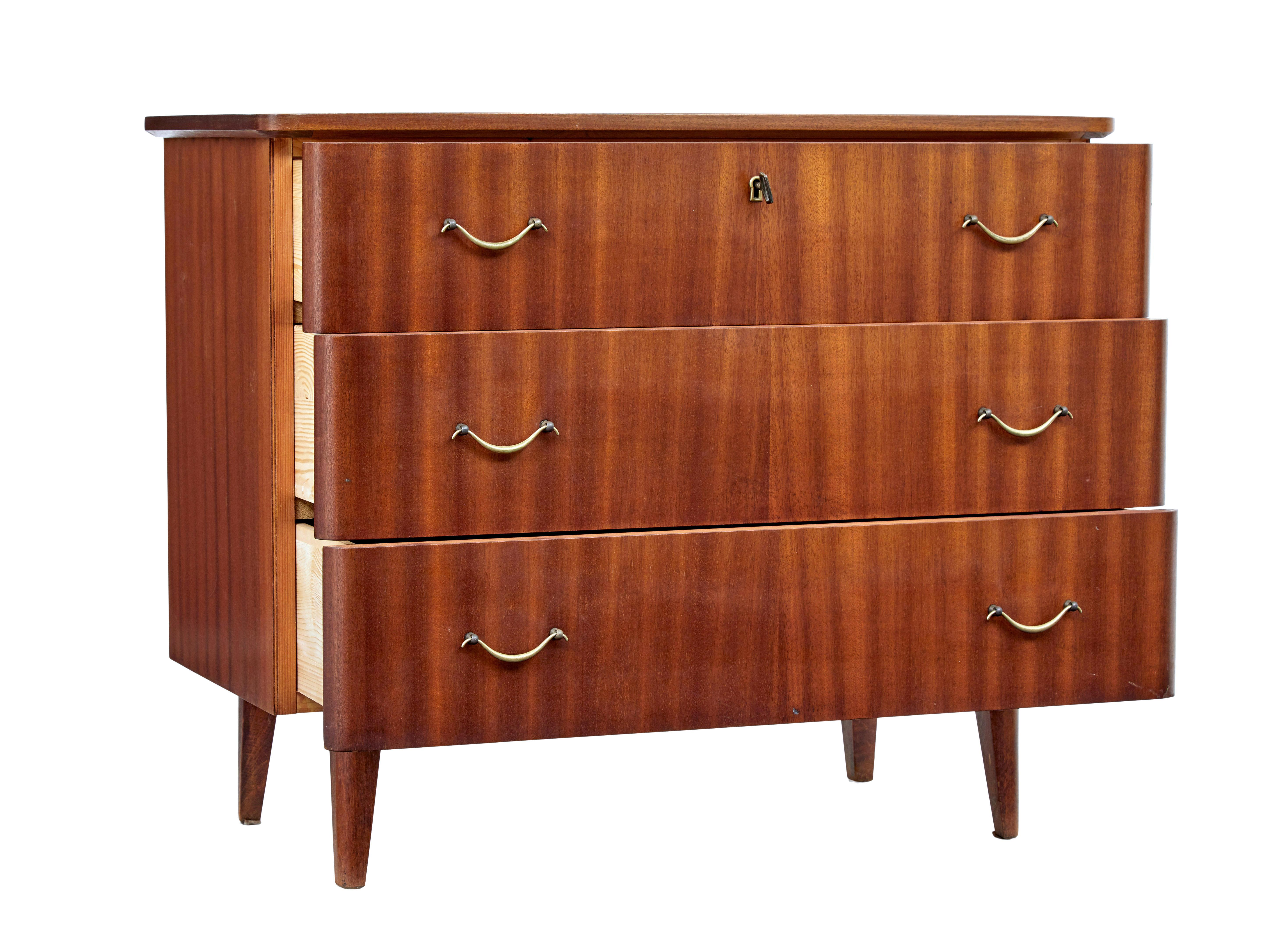 Commode en teck danois du milieu du 20e siècle, vers 1960.

Commode à 3 tiroirs au design scandinave des années 1960. Plaqué en teck et muni de poignées en laiton façonné.  Tiroir supérieur avec serrure et clé pour un rangement sécurisé.  Il repose