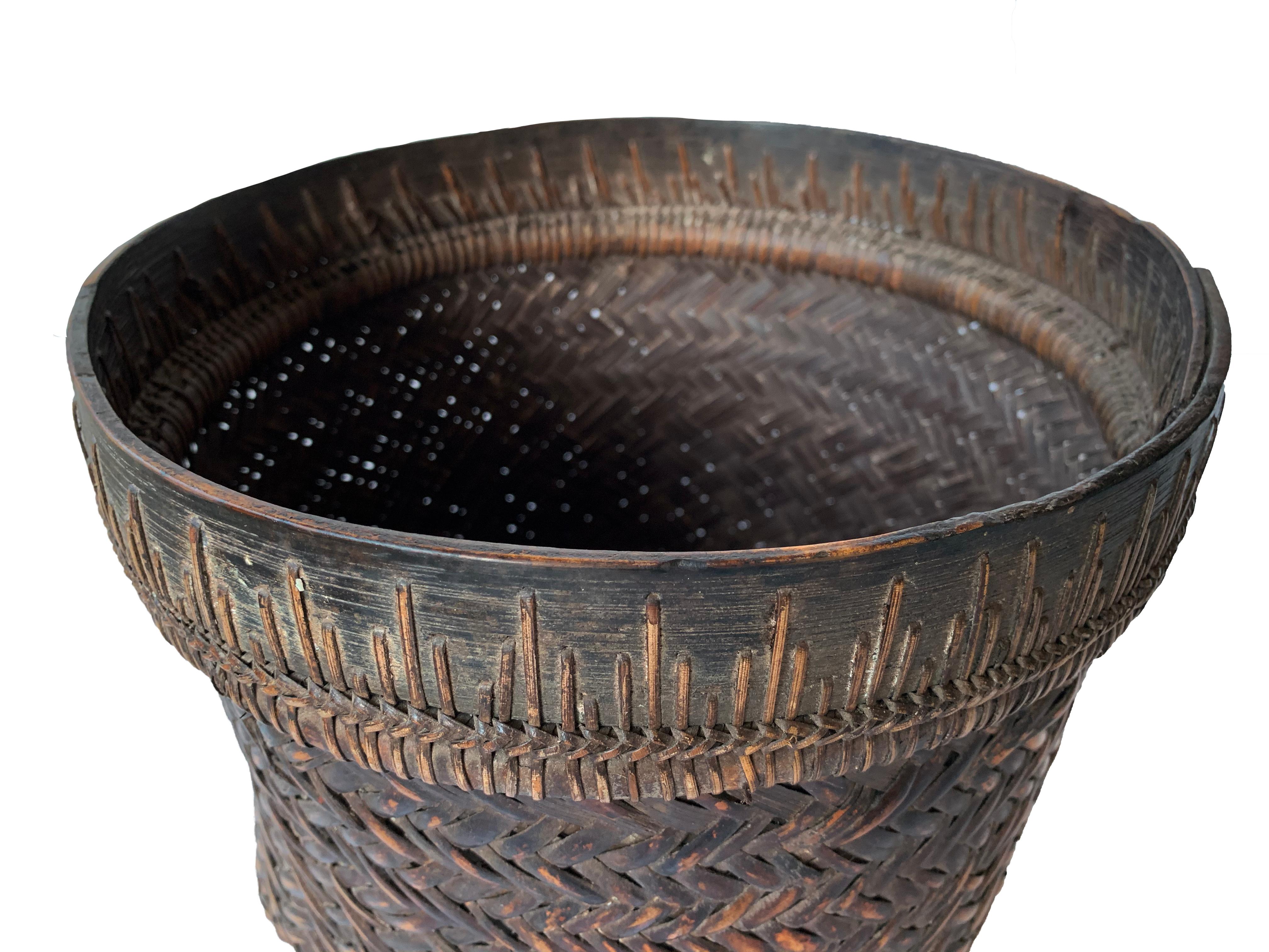 This mid-20th century hand-woven basket originates from the Dayak tribe of Borneo crafted with rattan fibres and an iron wood rim. These baskets were used to carry leaves, fruit, grain and wood and features wonderfully aged fibres and wood