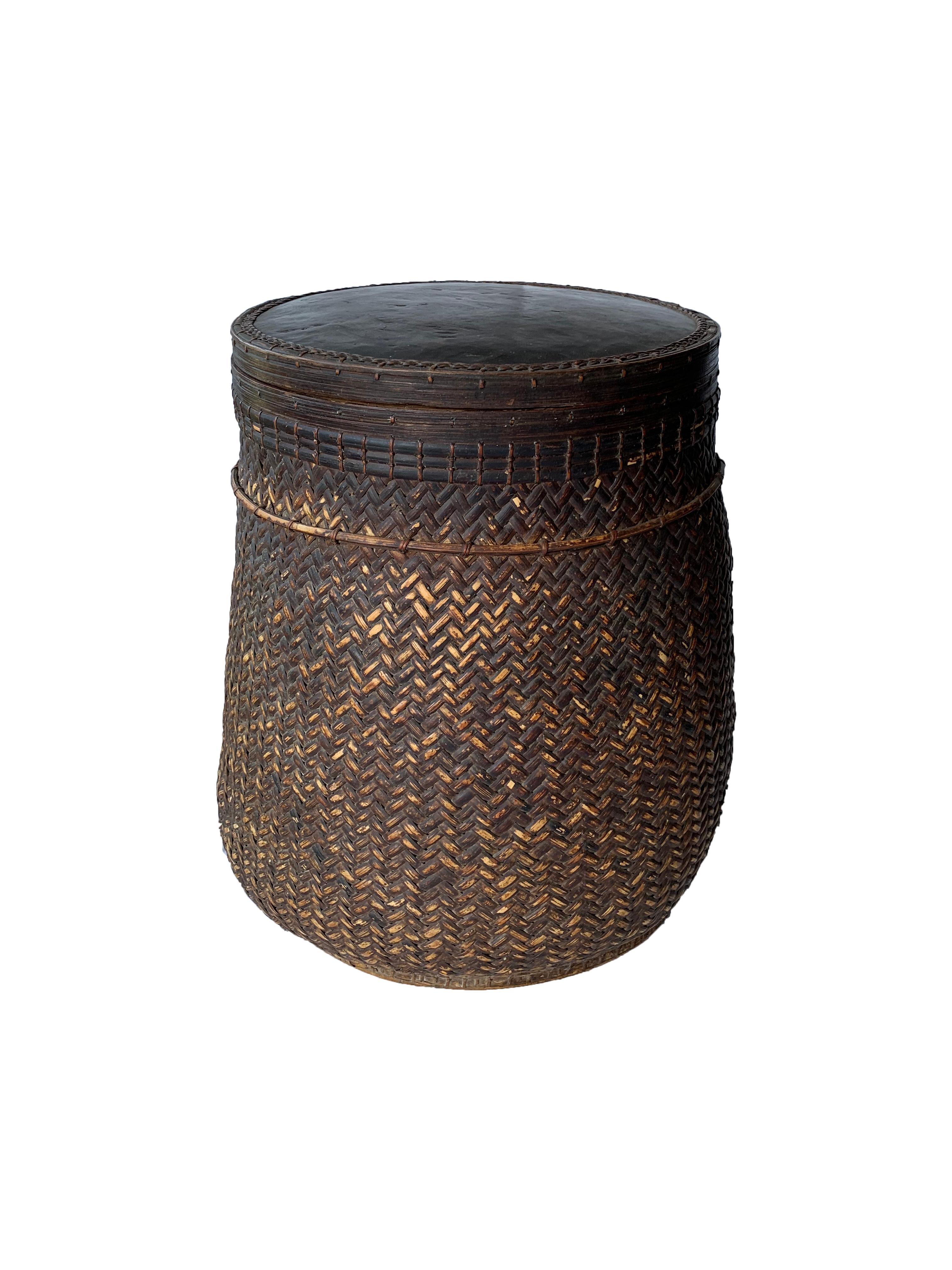 This mid-20th century hand-woven basket originates from the Dayak tribe of Borneo crafted with rattan fibres and an ironwood frame and rim. The hard top is also made from ironwood. These baskets were used to carry leaves, fruit, grain and wood and