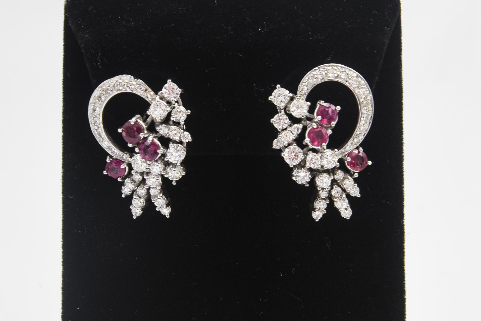 Elegant 1950s diamond and ruby earrings with a semi circle diamond ribbon that leads to a ruby and diamond spray.  These earrings sit beautifully on the ear and can be worn with the circle next to the ear or with the spray next to the ear which