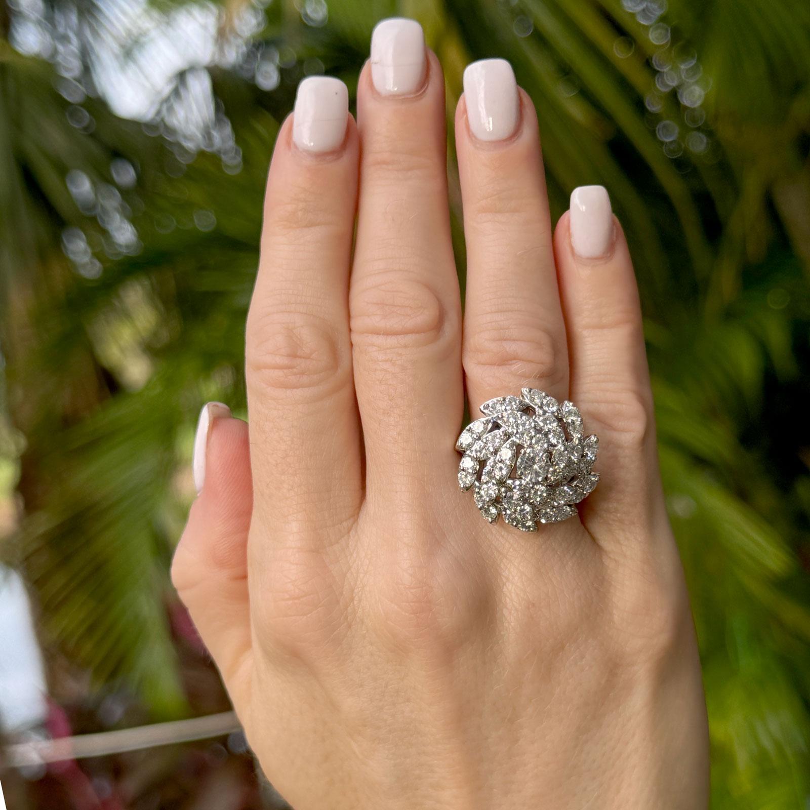 This vintage 14-karat white gold spiral diamond ring showcases a captivating design with a brilliant central diamond of approximately 0.50 carats, graded J in color and SI in clarity. Surrounding the center stone are 44 round brilliant-cut diamonds