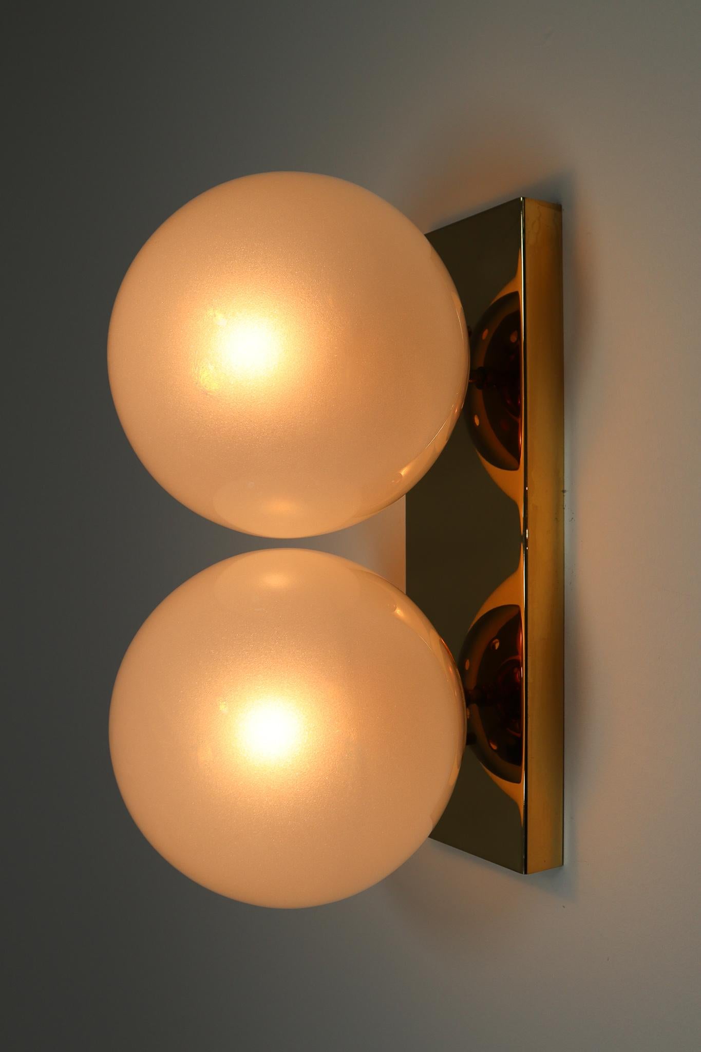 Mid-20th Century Brass Wall/Ceiling Lights White Frosted Glass Globes, 1960s

Double wall sconces / ceiling lights with rectangular brass backplates and hand blew frosted glass globes. The bulbs are connected directly to a brass vertical/horizontal