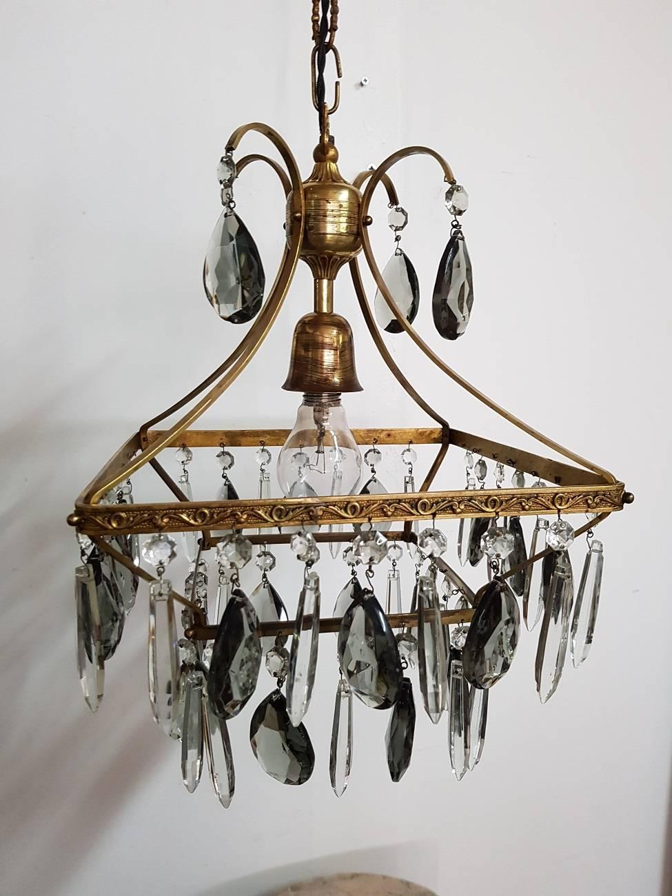 Vintage mid-20th century glass chandelier with glass prisms and decorated with relief pattern of curls in the frame. It is in a good condition with new vintage wire and all the pegs have been cleaned of which have a few small chips.

The