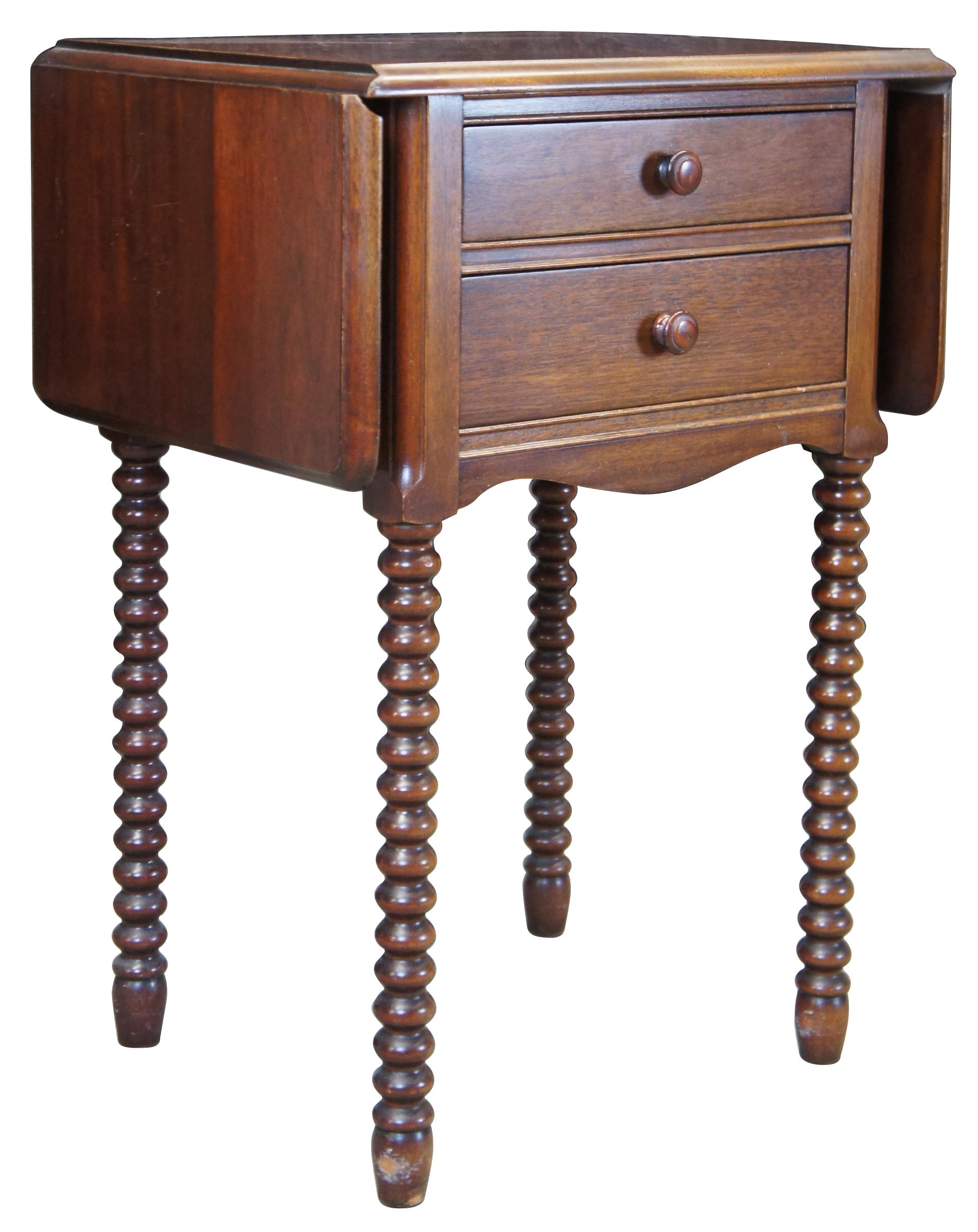 Mid-20th century Early American style dropleaf side table. Made from mahogany with a cherry stain. Features two drawers and long ribbed / spool legs.
    
Leaves add 10