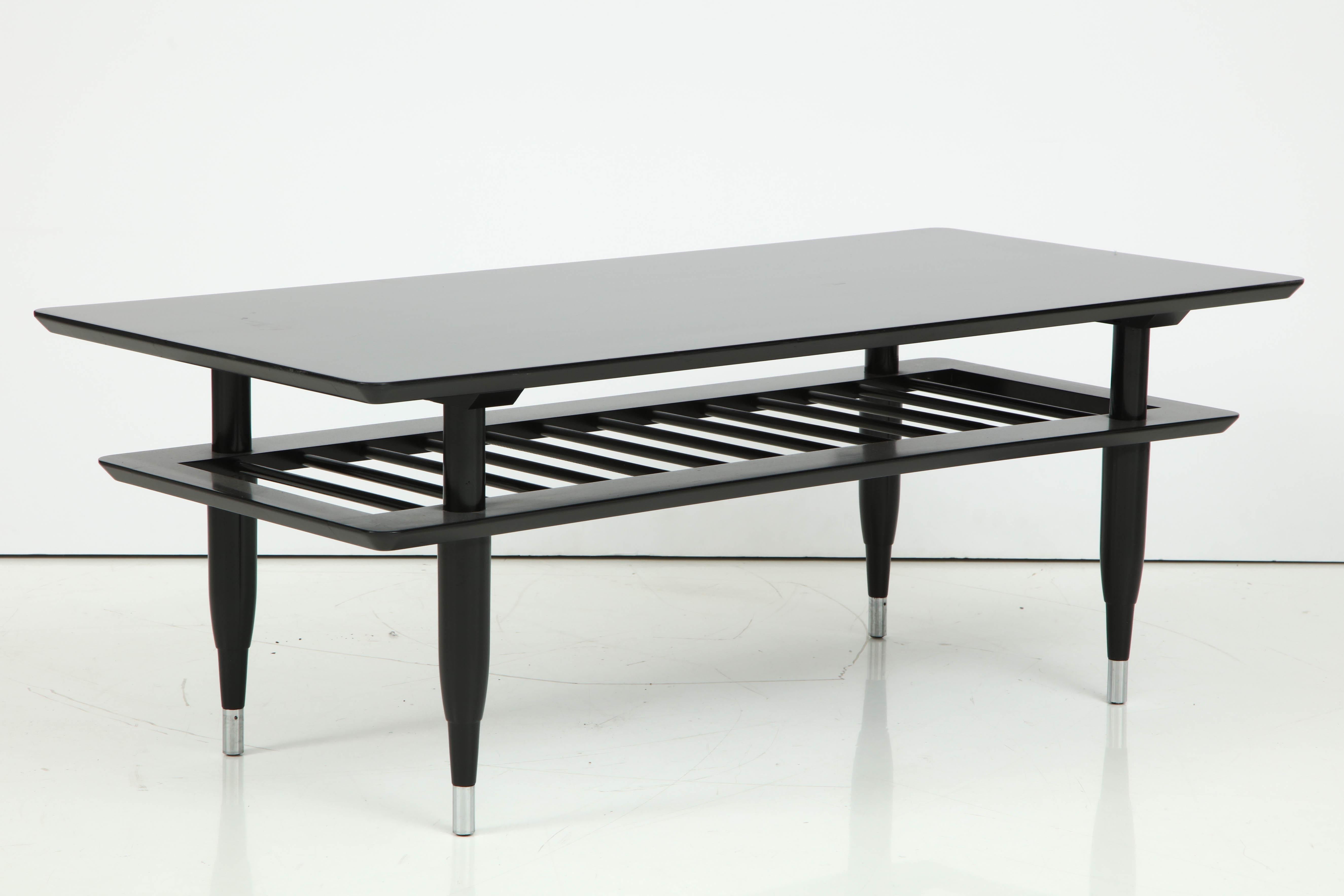 Mid-20th century ebonized two-tier cocktail table, slatted lower shelf, round tapered legs.