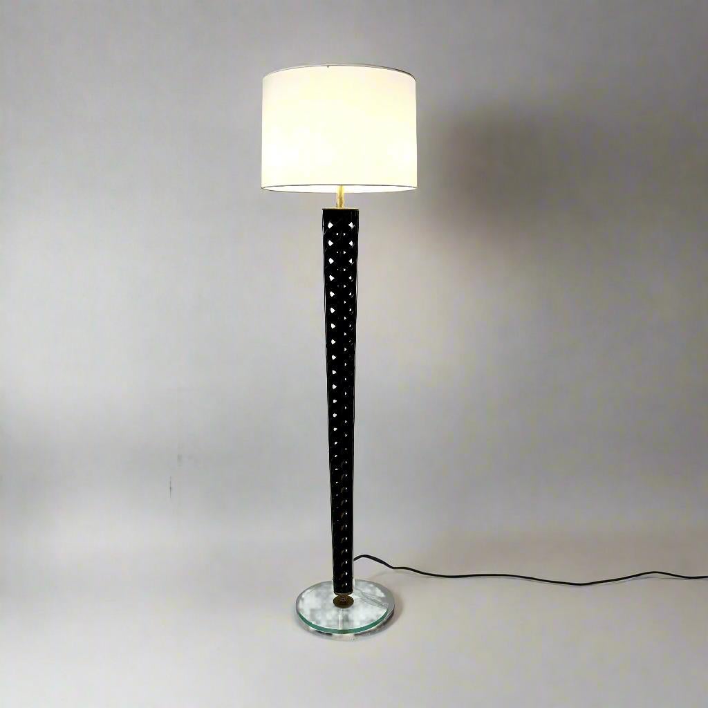 Elegante Lámpara de Pie Elipse en Espiral de madera y latón. El fuste central de la lámpara de pie es una elipse de celosía de madera calada, que va aumentando de tamaño desde la parte superior y estrechándose en la inferior. La madera de acabado
