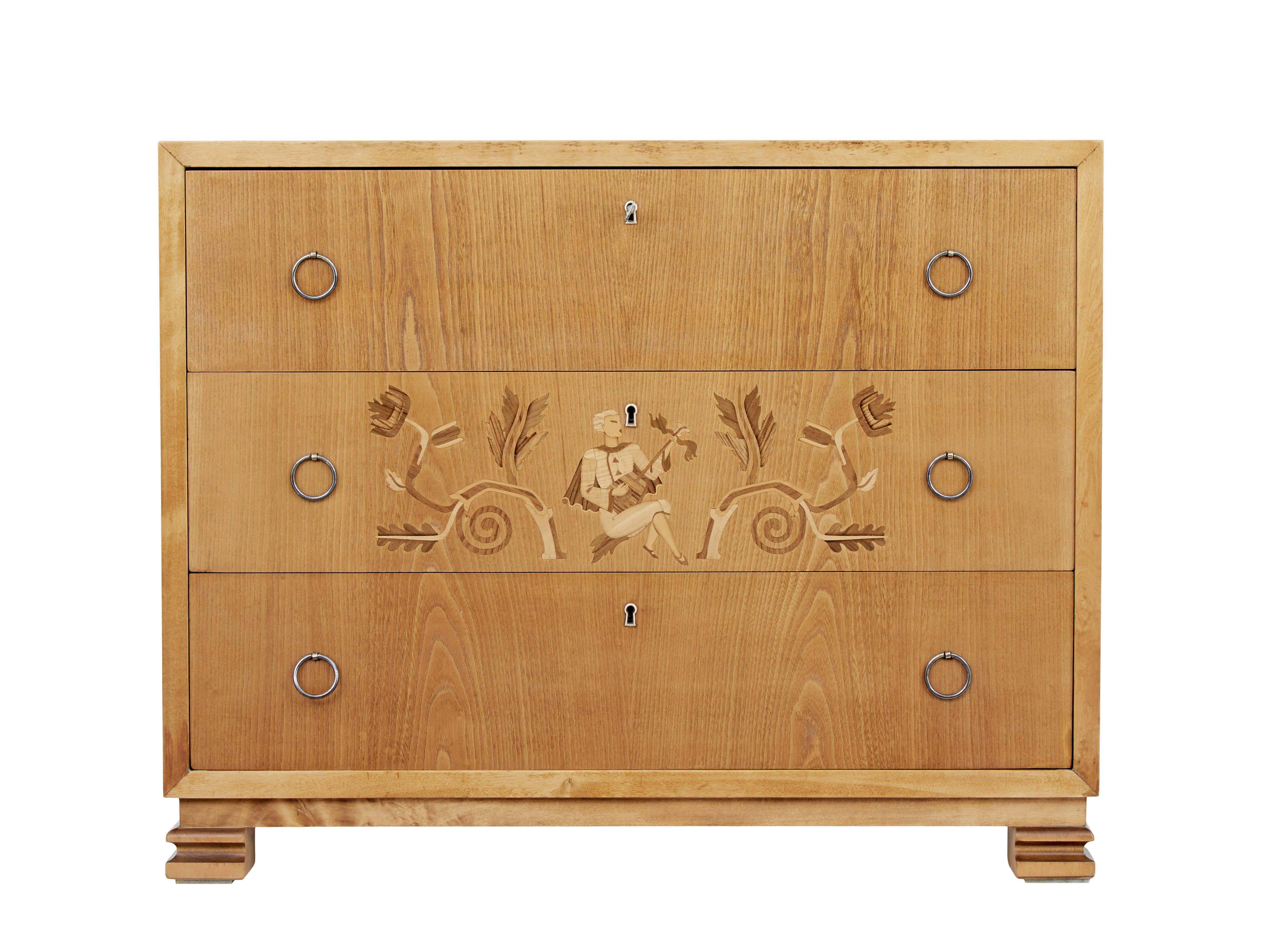 Mid-20th century elm and birch Swedish grace chest of drawers, circa 1940.

Superb quality 3 drawer chest. Outer birch frame with some stunning burring, drawers veneered in elm, with a beautifully inlaid middle drawer. Each drawer fitted with ring