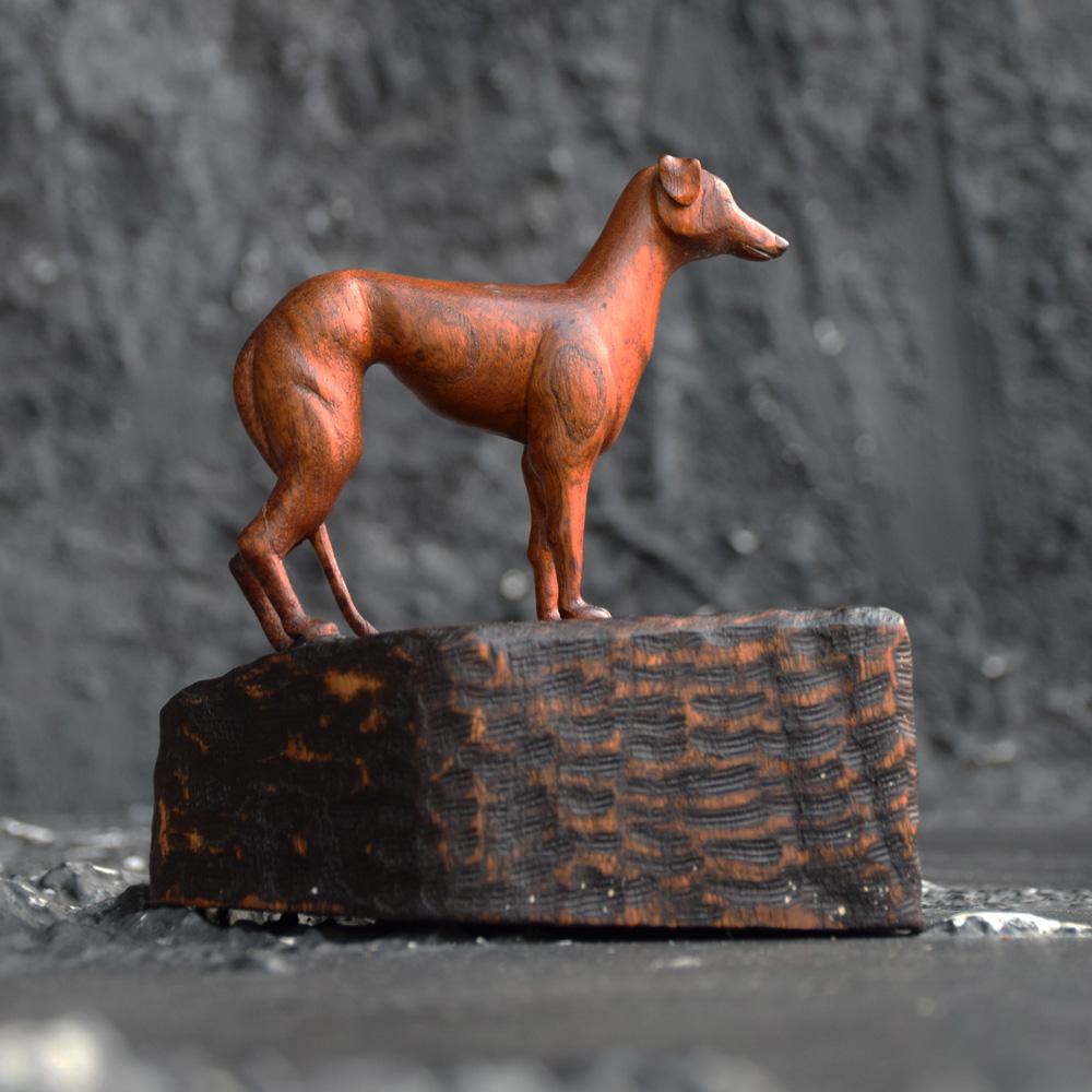 A unique mid-20th century Folk Art carved wooden whippet dog figure, standing on a bespoke make stand with a wonderful overall carved look. The carved dog shows detailed carving and proportion as shown in the photos provided. A highly decorative and