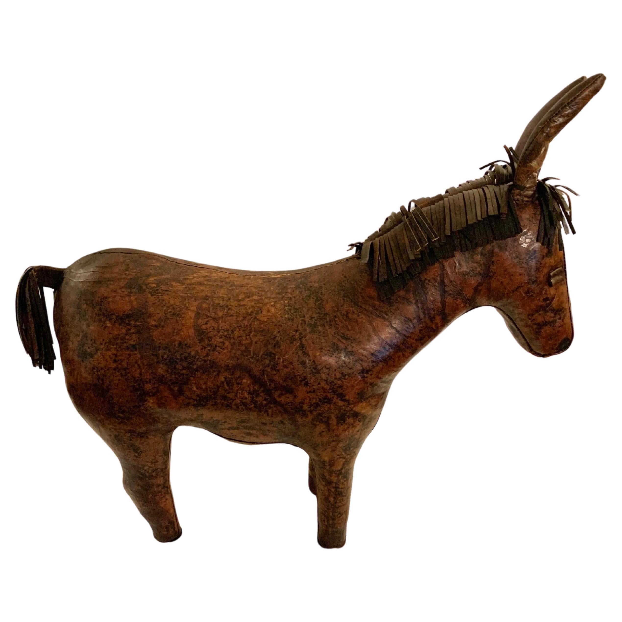 This Mid 20th Century English Leather Donkey Footstool was styled after Dimitri Omersa for Abercrombie & Fitch in the mid 1900's. The piece is handcrafted from high quality leather that shows a beautiful patina throughout. Each of the four legs