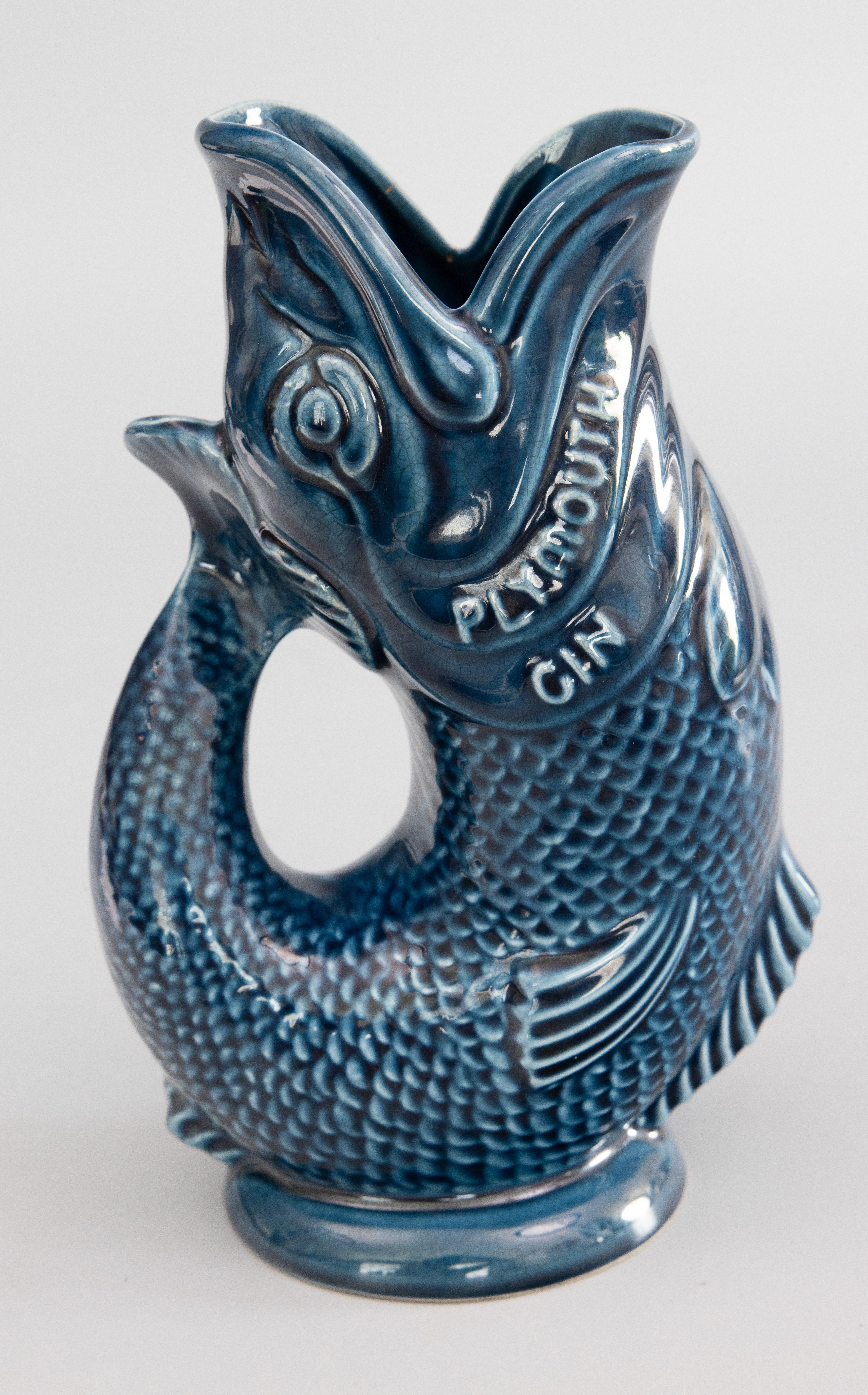A fabulous vintage English blue gurgling fish glazed ceramic pitcher or glug jug by Dartmouth pottery, made in Devon, England, circa 1960. Maker's mark on reverse. This stylish pitcher is a lovely glazed blue color advertising 