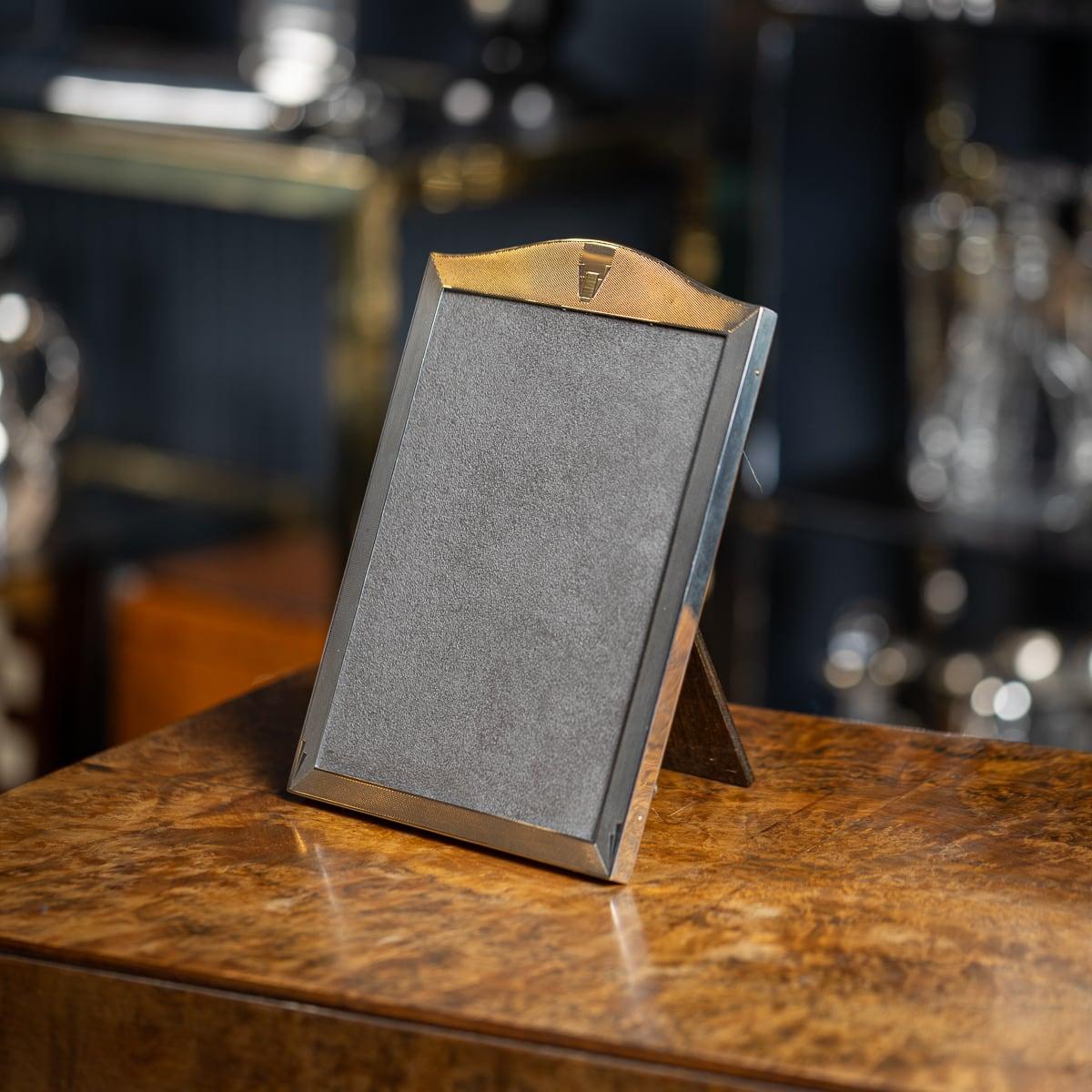 Marco de fotografía de plata maciza de fabricación inglesa de mediados del siglo XX, de forma rectangular con acentos geométricos, cubierto tras un cristal y sobre un soporte de puntal. Una pieza realmente varonil y una magnífica pieza histórica que