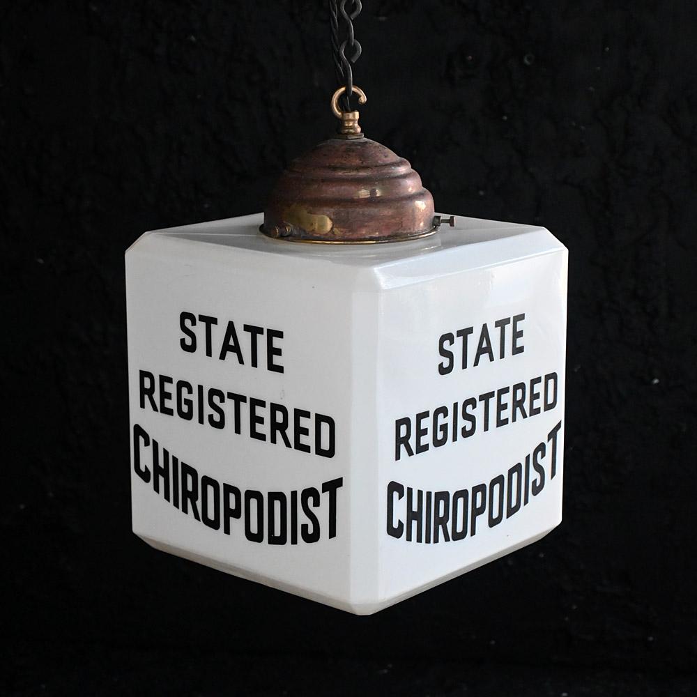 Mid-20th century etched glass trade sign light.

A highly unusual and quirky mid-20th century trade sign light promoting Chiropodist services. Text in etched milk glass on 2 sides. With a copper hanging gallery in place, recently re-wired to a UK