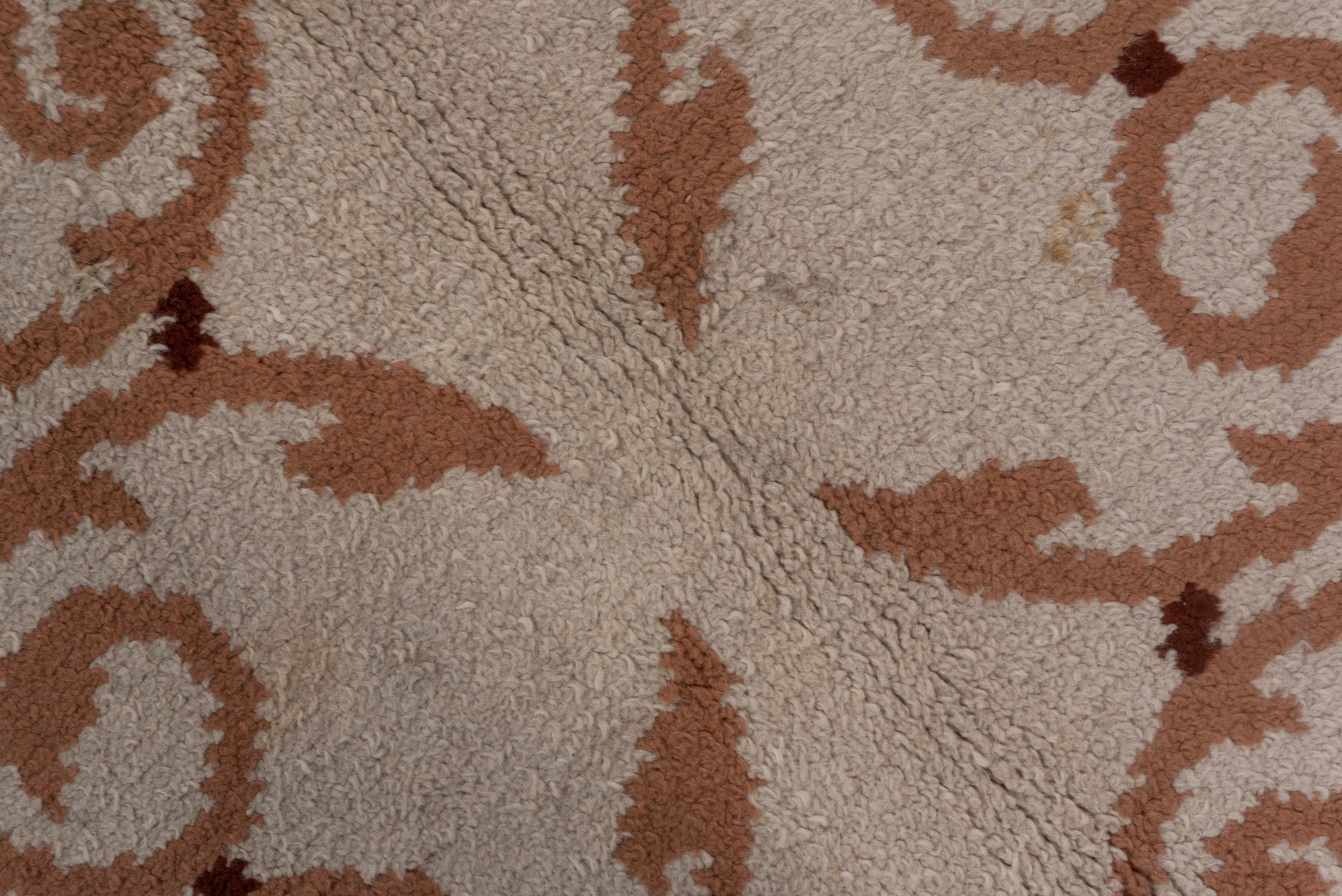 This excellent condition piece has a simple two -tone narrow wavy border framing the sand ground with a salmon-brown open volute pattern in the Modern style.