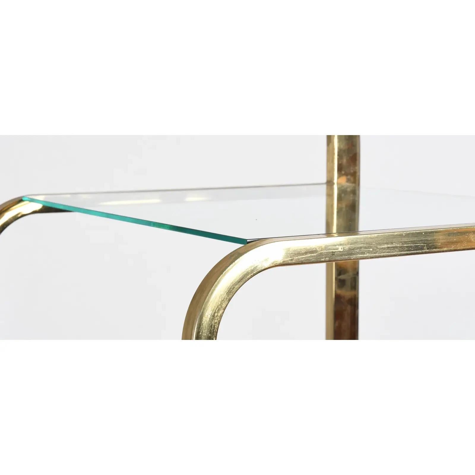 Un'etagere o scaffale da esposizione contemporaneo a due sezioni, con cornici in tubo quadrato di ottone curvato e ripiani in vetro trasparente alternati di varie dimensioni. Questo design espandibile trae ispirazione da Milo Baughman e dallo stile