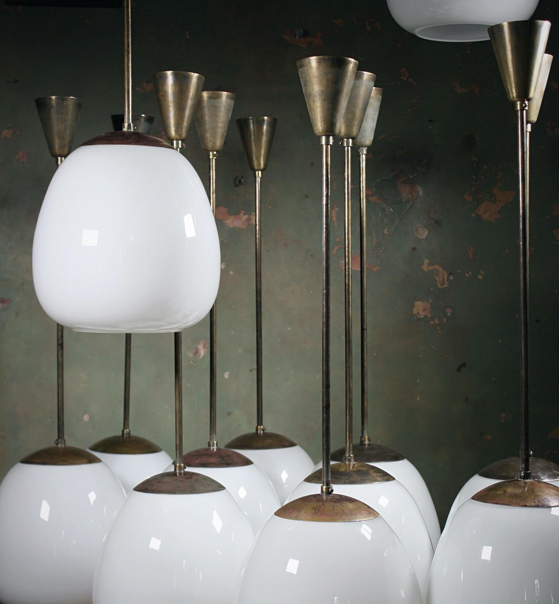 A run of 16 (3 sold) extra large tulip opaline glass pendants with their original brass monk cap galleries, brass stems and spun brass ceilings roses.

All metal sections have age related oxidisation, all glass is in great condition. 

Removed from