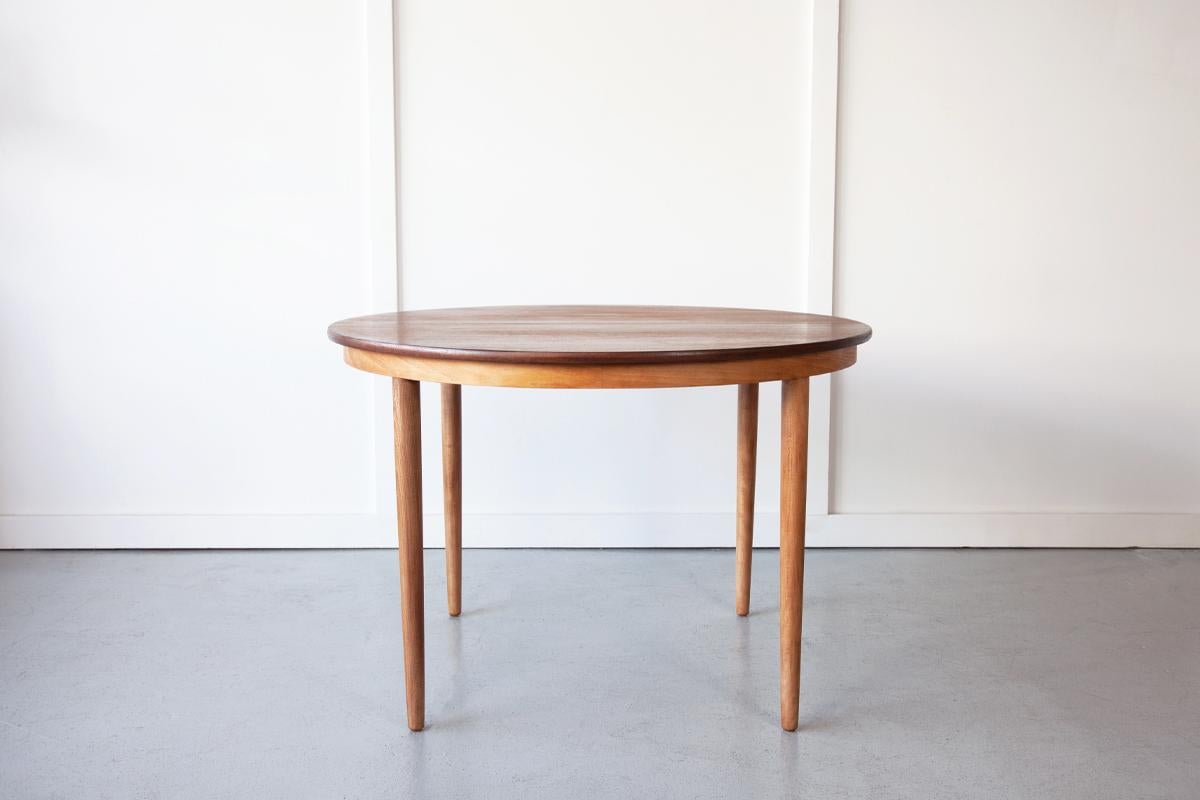 A beautiful round dining table produced by Farstrup Møbelfabrik in teak. This table features screw-in solid beech legs and one drop in leaf which extends the tables length for guests. The full length of the table with the additional leaf is 158cm