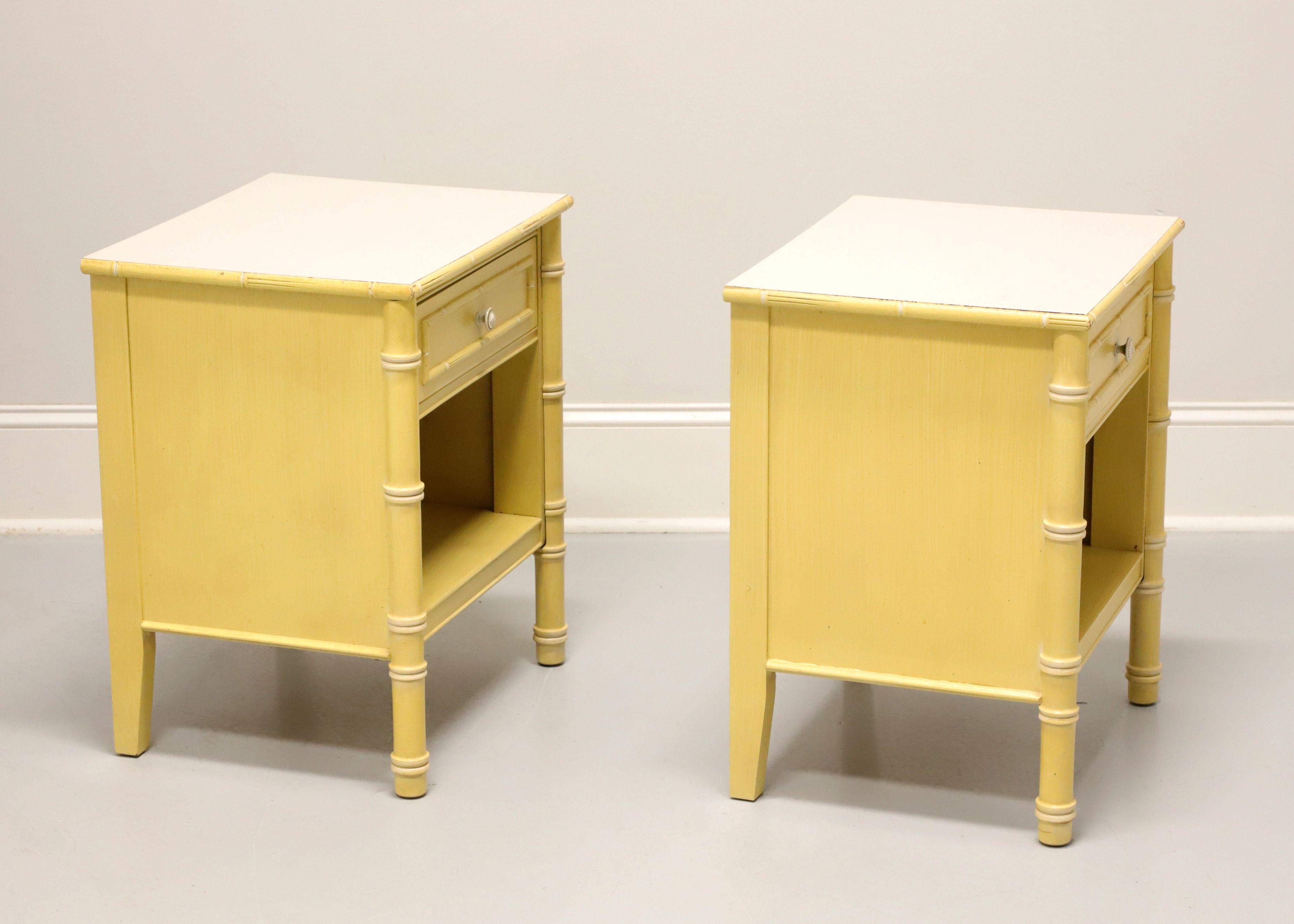 A pair of Asian influenced nightstands, unbranded, similar quality to Drexel or Thomasville. Faux bamboo painted a shade of yellow, white laminate top, antique brass hardware, round faux bamboo styling to front legs and square back legs. Features