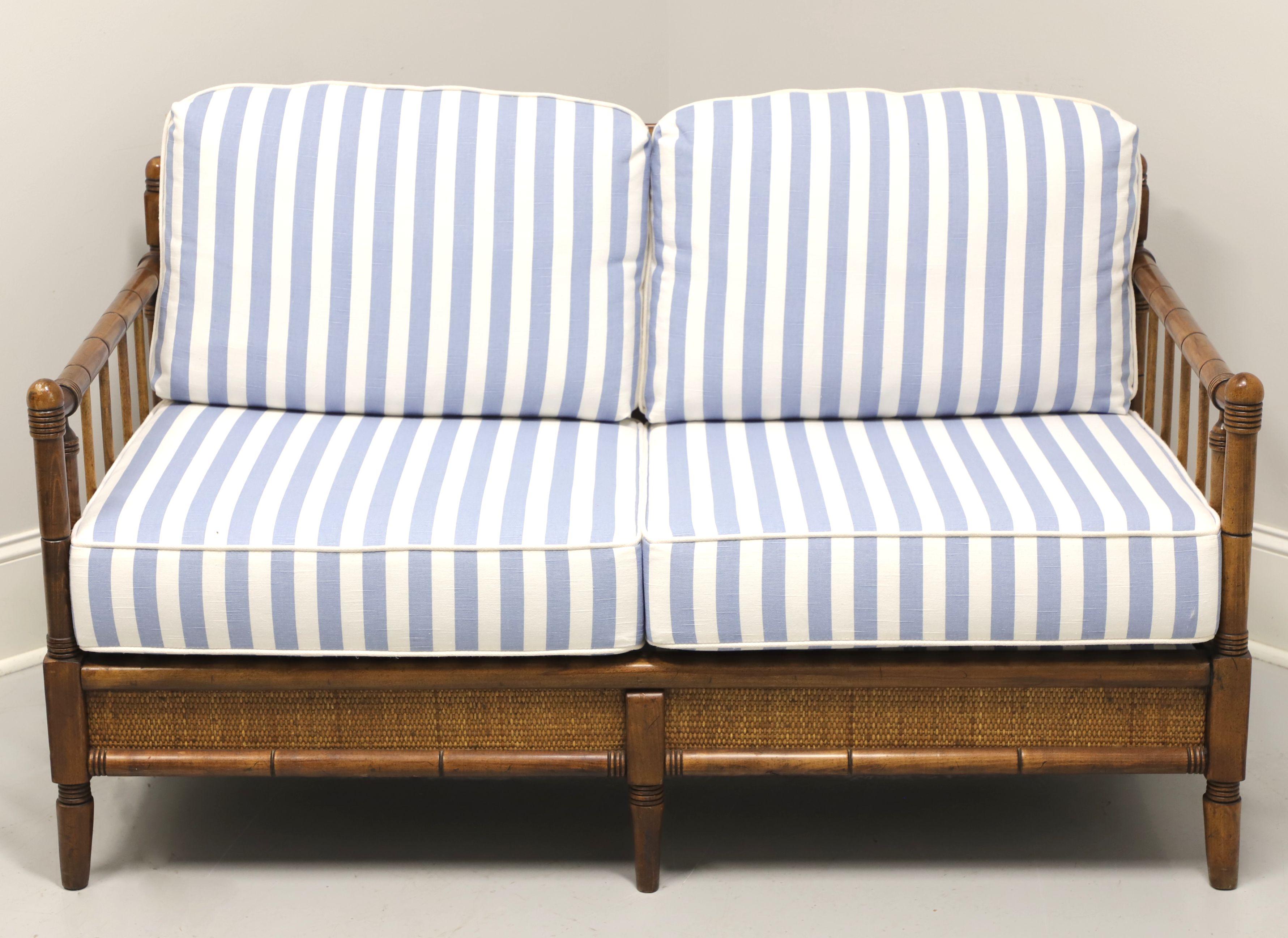 A mid 20th century British Colonial style settee by Broyhill Premier. Faux bamboo hardwood frame, cane trim to apron, rounded slat arms, open slat back, cloth upholstered seat support, light blue & white colored fabric upholstered back & seat
