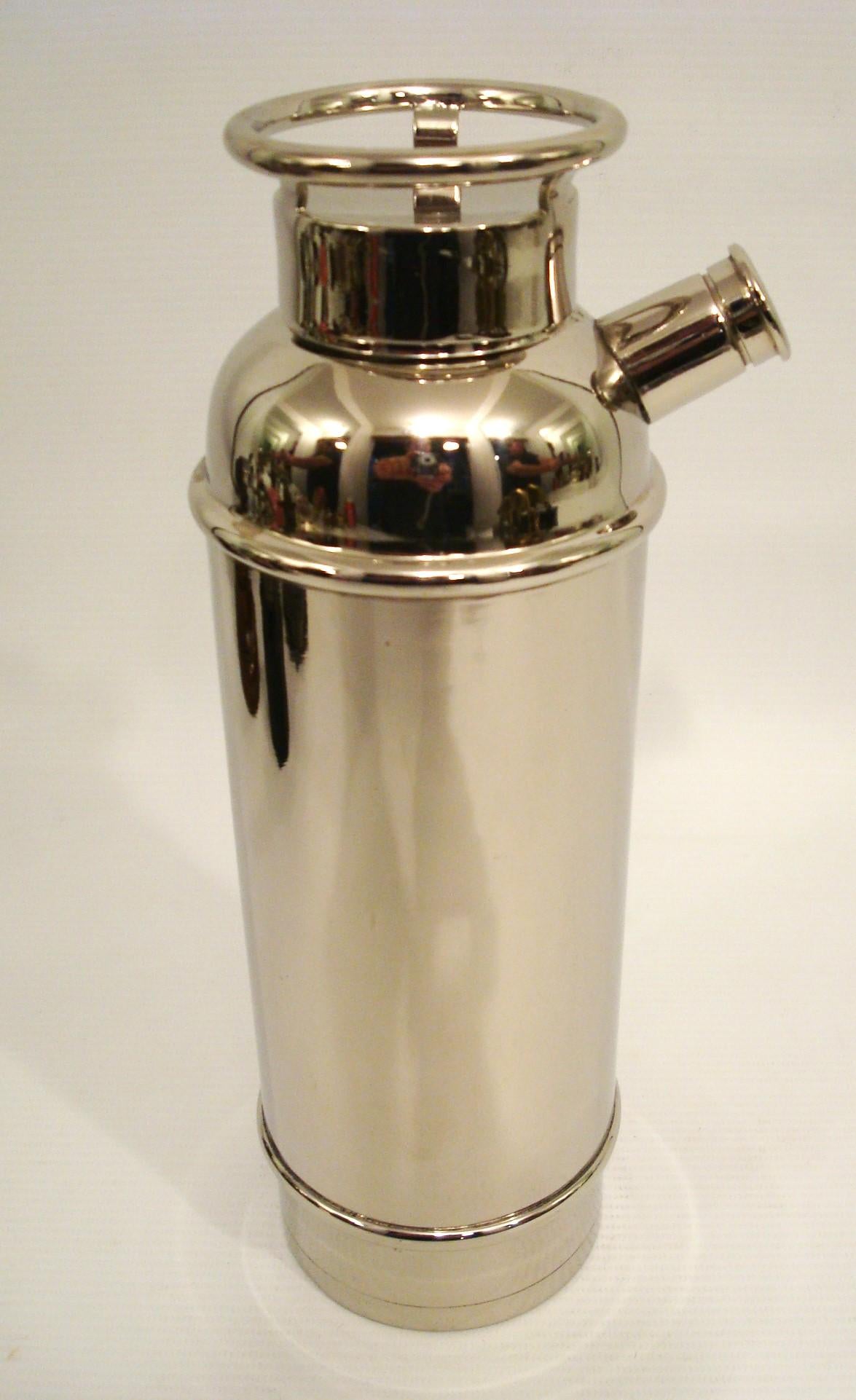 This is a novelty Silvered Fire Extingisher Cocktail Shaker. The wheel top gives access to the body and the knurled end of the spout, which contains a filter, also unscrews for pouring, as shown in the photographs.

Condition: Very good. The plate