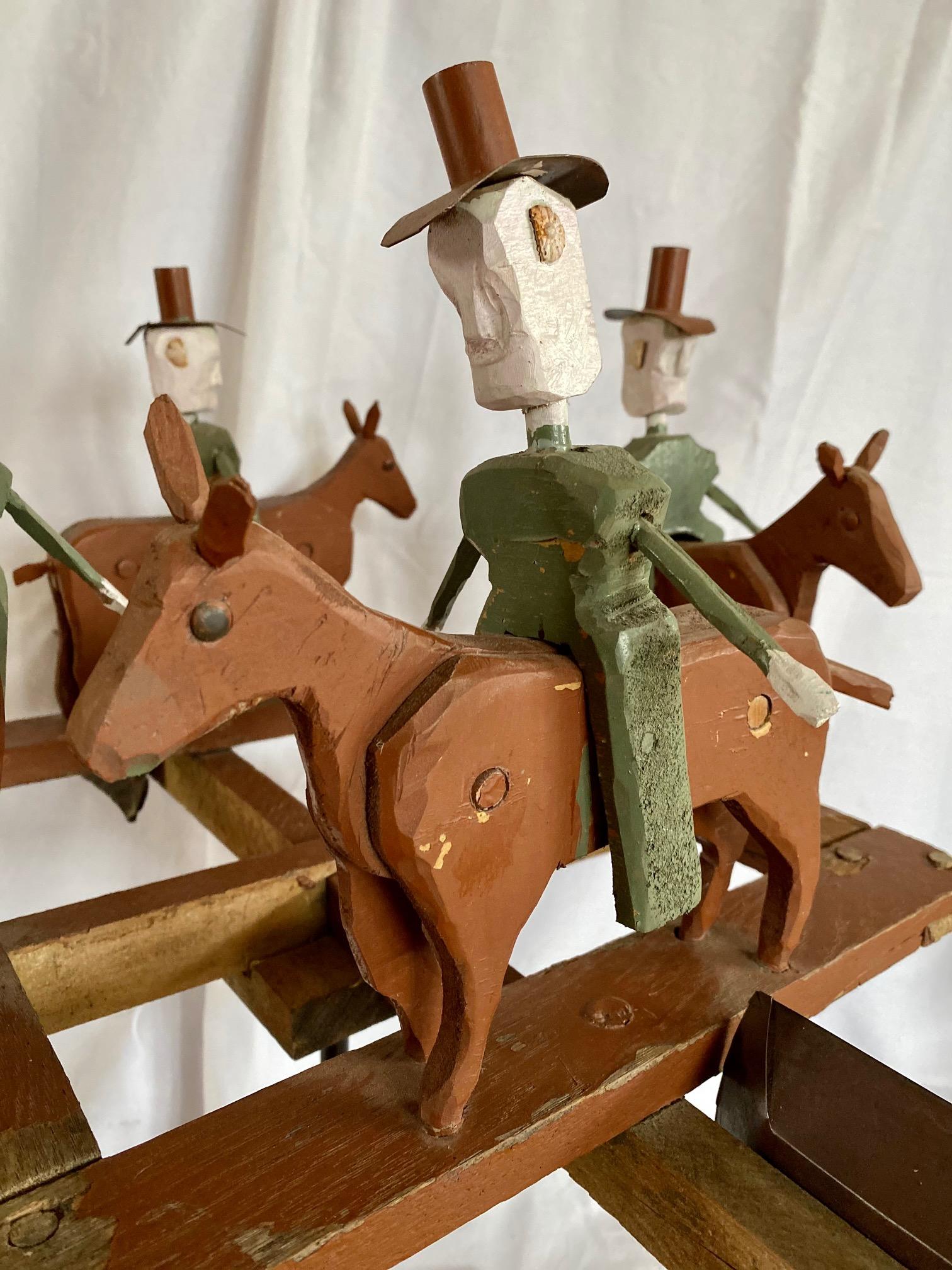 Mitte des 20. Jahrhunderts Folk Art Cowboy Rodeo Whirligig, ca. 1940er bis 50er Jahre, bestehend aus vier geschnitzten und bemalten Cowboys auf Pferden, die im Kreis reiten und vom Wind gedreht werden. Jede naive Figur hat einen geschnitzten Kopf