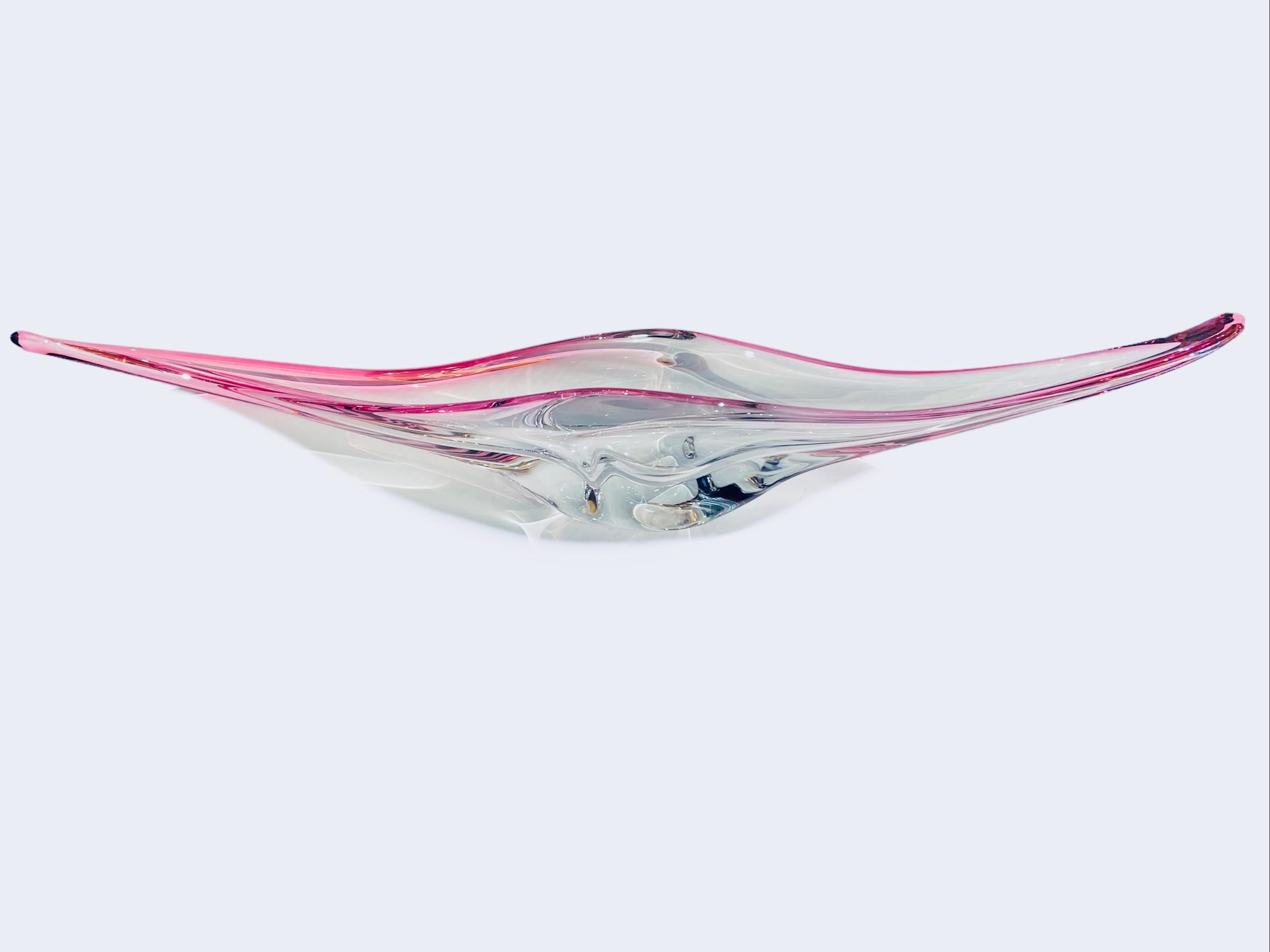 This is a mid century French Art Crystal Centerpiece. It depicts an elongated mantraya like shaped clear crystal vase/bowl with dark pink borders.