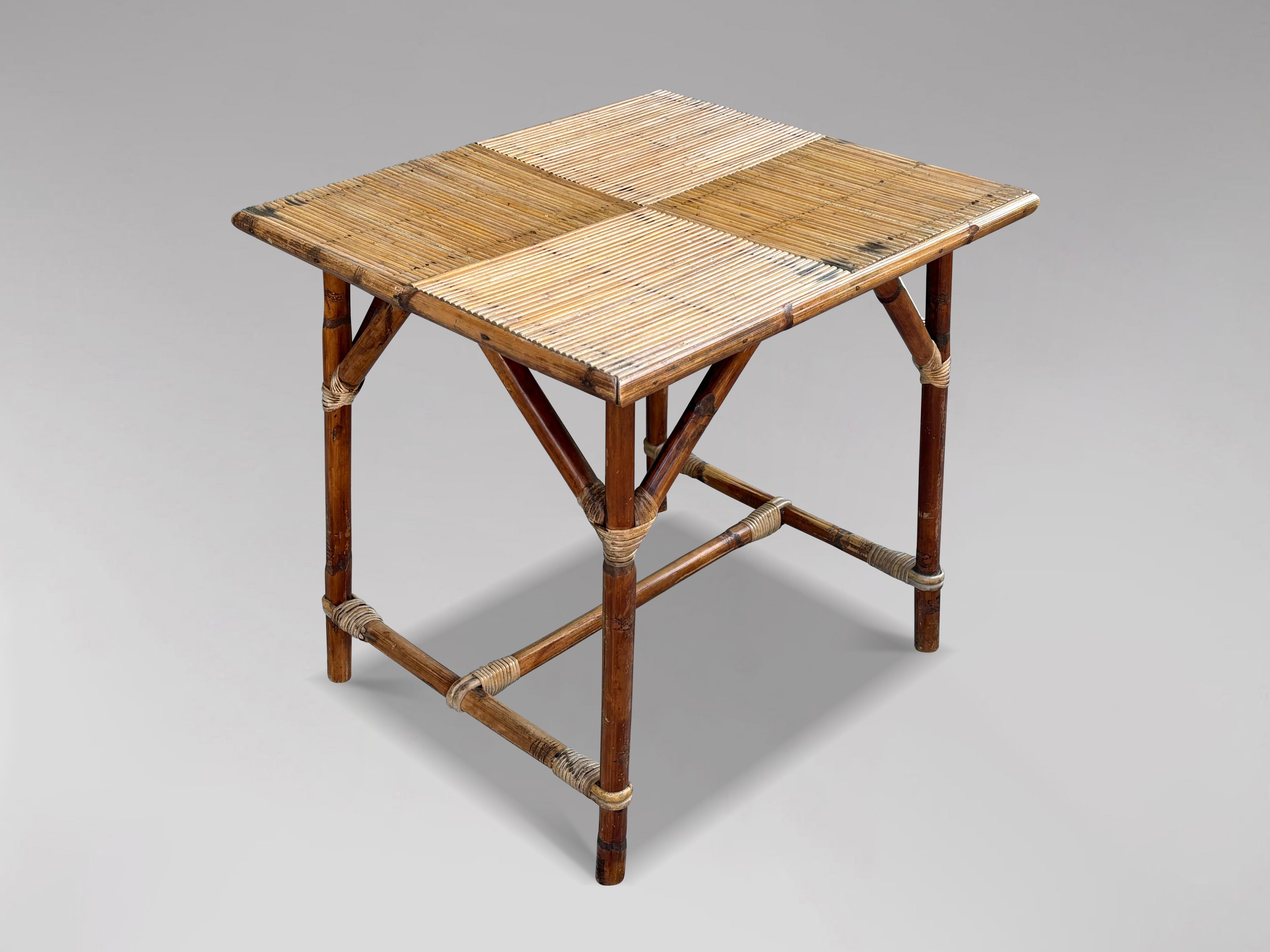 Esta mesa auxiliar o de comedor francesa de mediados del siglo XX, diseñada por Audoux y Frida Minet, data de la década de 1950. Presenta una tapa rectangular de ratán a cuadros, sostenida por cuatro patas de bambú adornadas con detalles de ratán