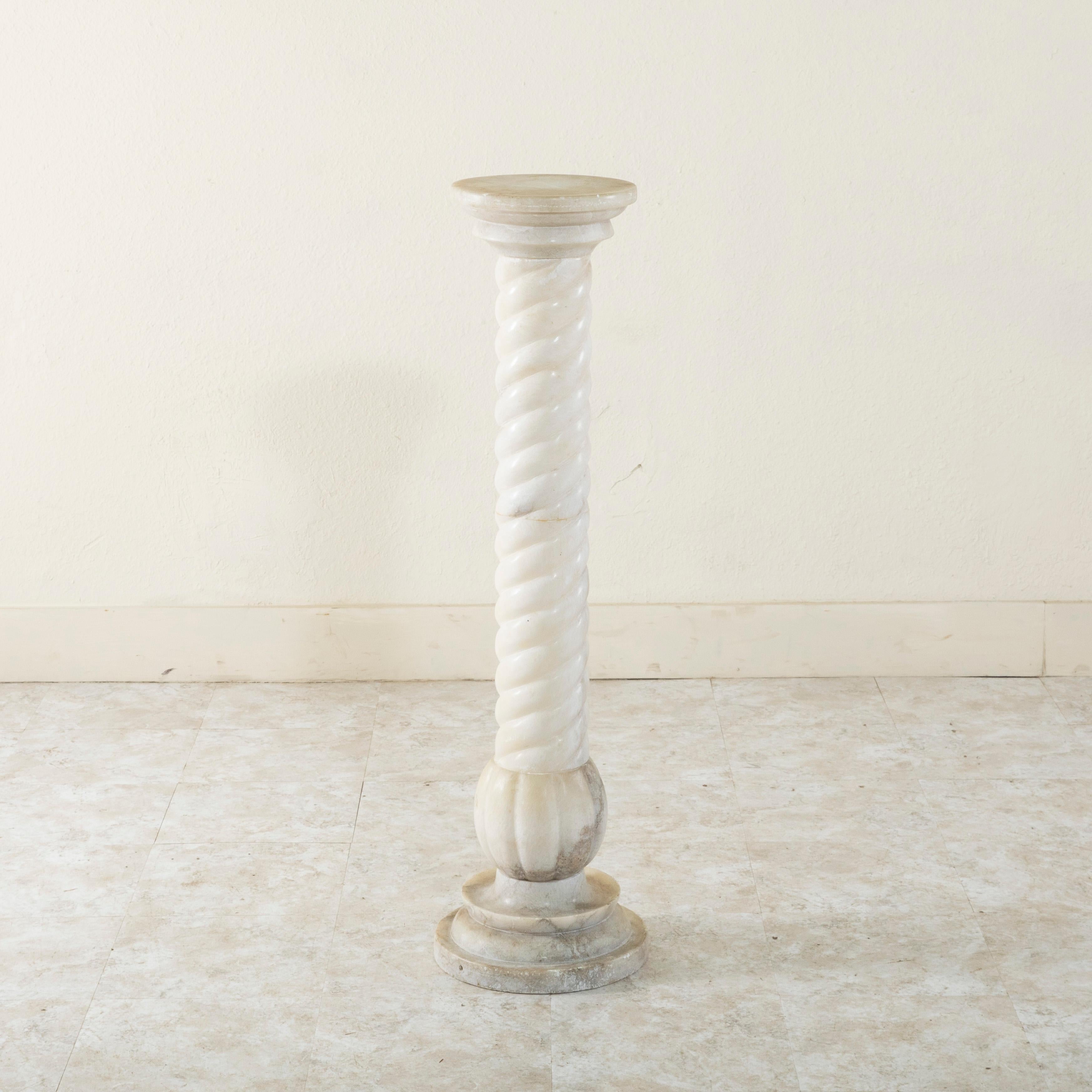 This early twentieth century French alabaster column or pedestal stands at 42 inches in height and features a spiraling barley twist along its central pillar. Resting on an 11.5 inch diameter plinth base, this column would be a wonderful addition to