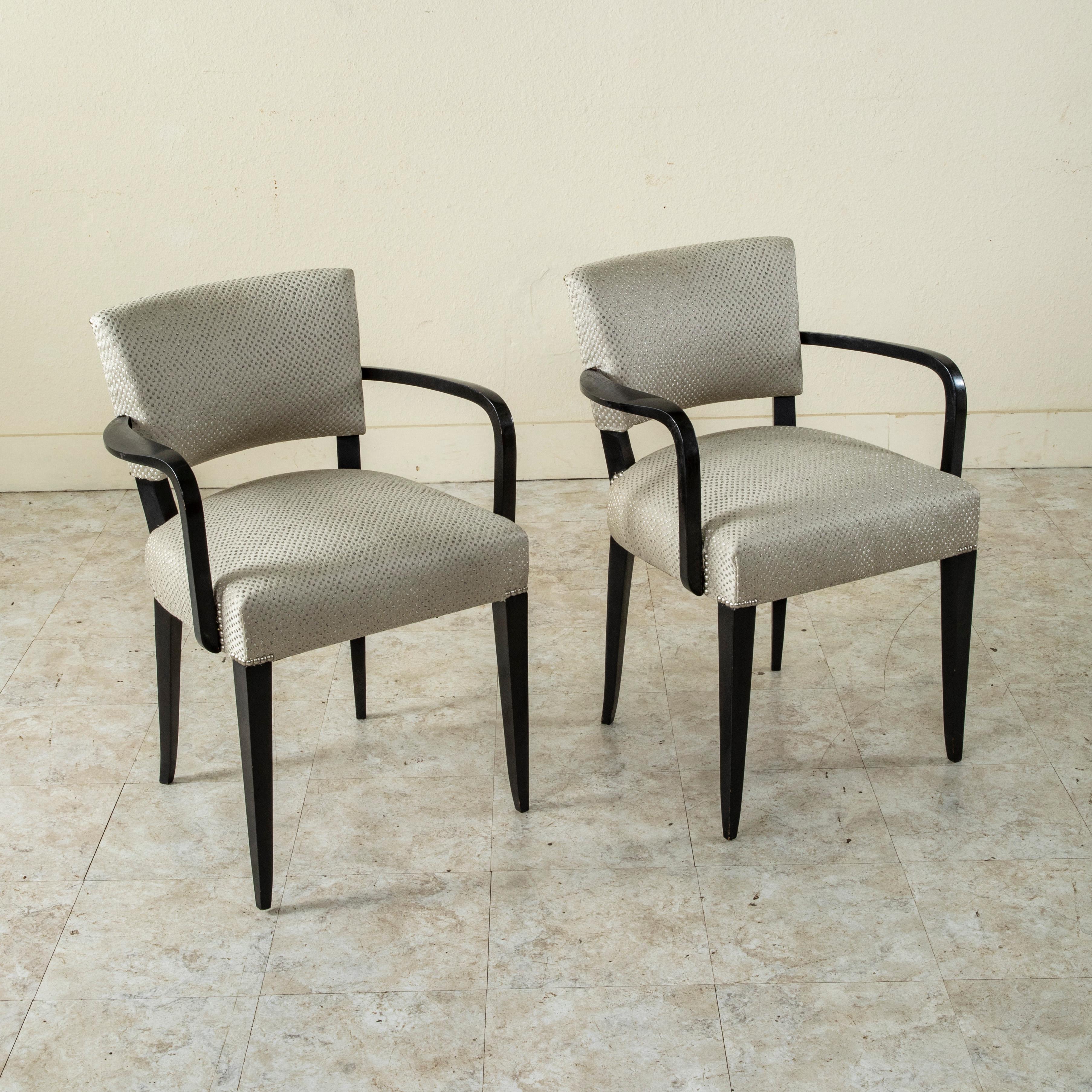This pair of mid-twentieth century French chairs features black lacquered frames with curved armrests. The French refer to these as bridge chairs since this style was popular at the bridge table in the 1940's. Newly upholstered in France and