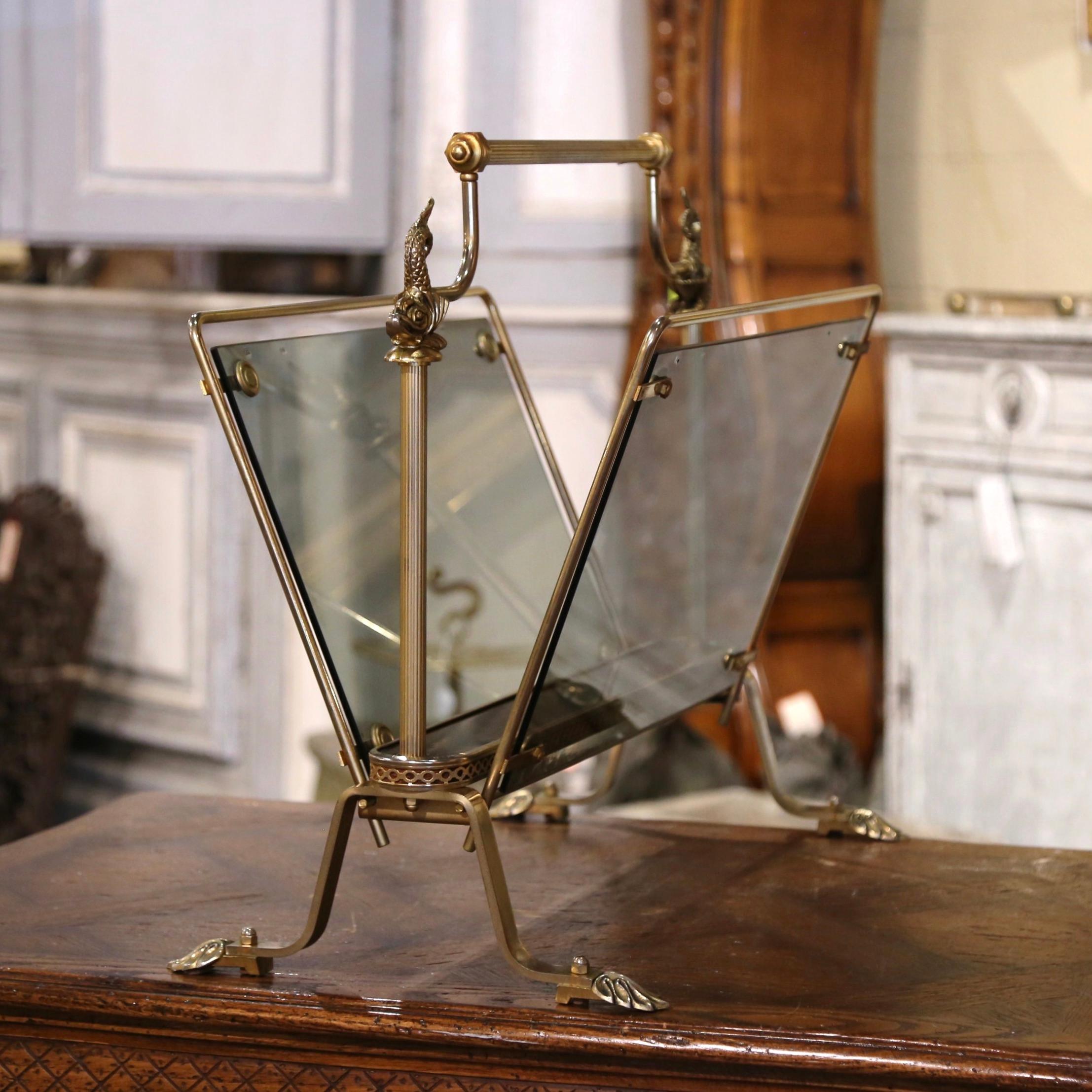 Keep your newspapers organized and neat inside this elegant vintage magazine holder. Crafted in Paris, France circa 1950 and attributed to Maison Jansen, the rack is built of brass and smoked glass. It stands on scrolled feet ending with acanthus