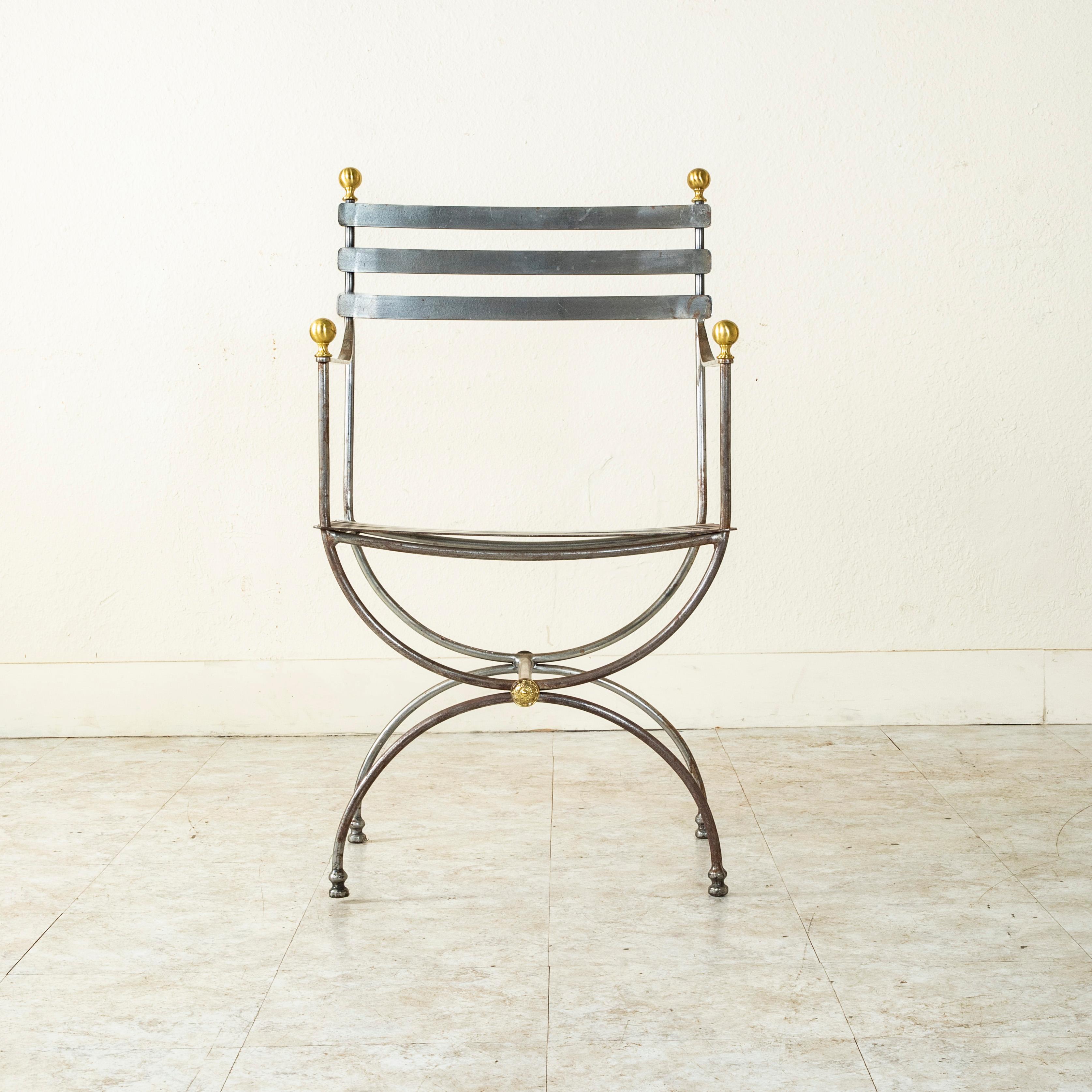 This Mid-20th Century French steel armchair features steel slats that form the seat and seat back. The seat rests on legs made of two opposing half circles joined by a stretcher. A brass rosette details each end of the stretcher, and the armrests