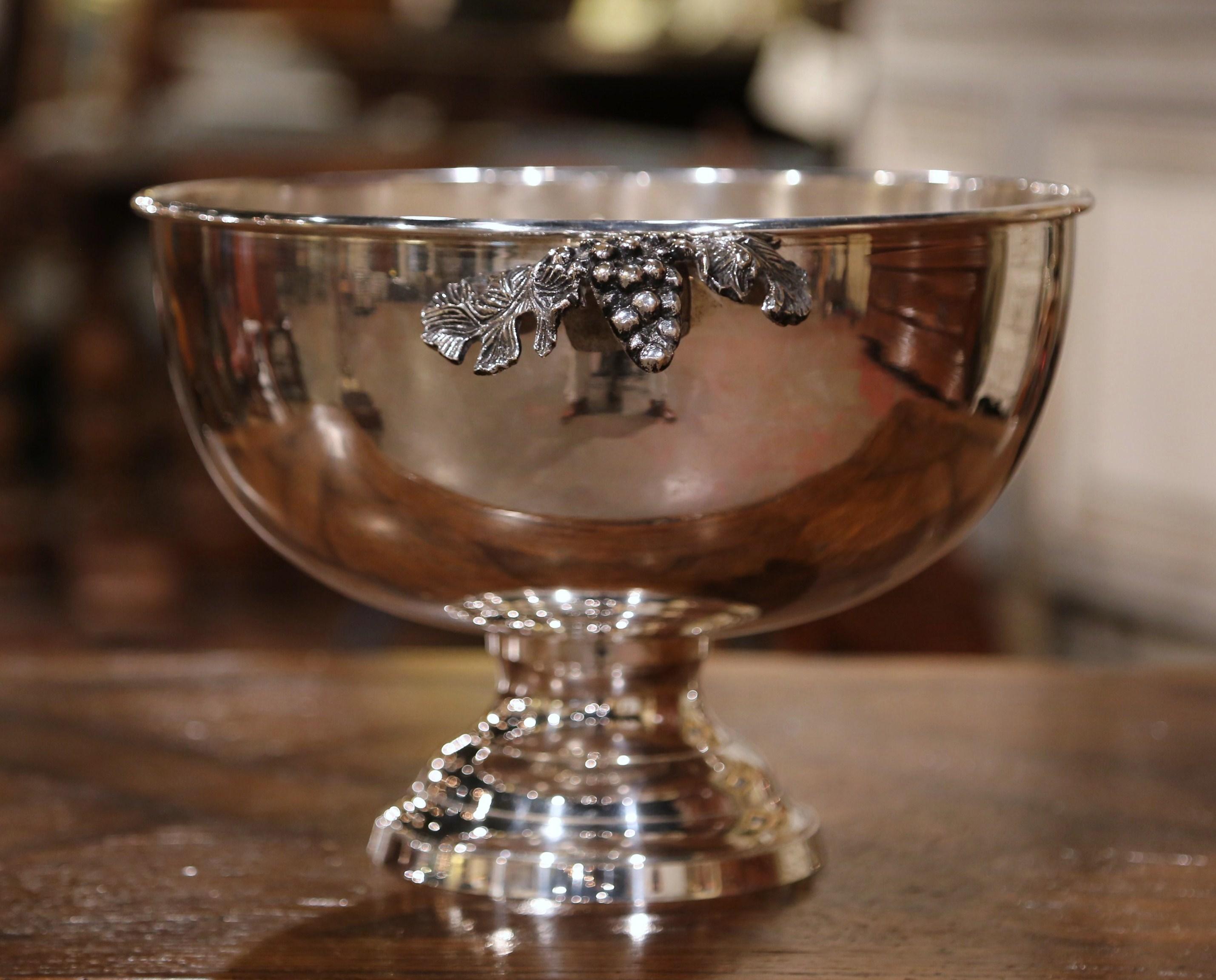 Keep your wine or champagne chilled in style with this elegant round bowl; crafted in France circa 1970 and made of silver plated over brass, the circular bowl stands on a round base; it features intricate decorative handles with grapes and leaves