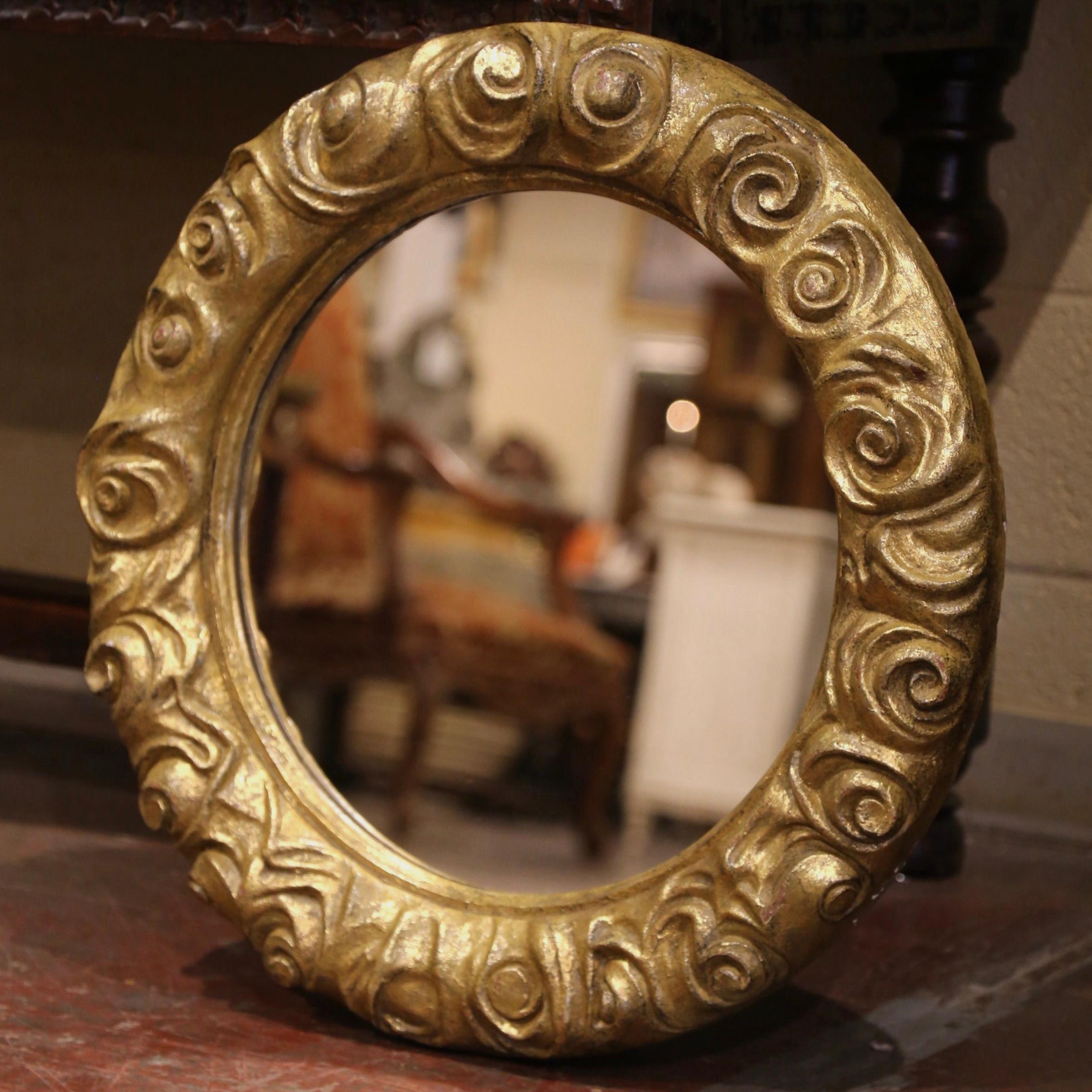 Create a focal point in any room with this gleaming antique wall mirror. Hand carved in France circa 1960, and round in shape, the mirror is decorated with carved rose and flower motifs in high relief. The piece has a shape and shimmering texture