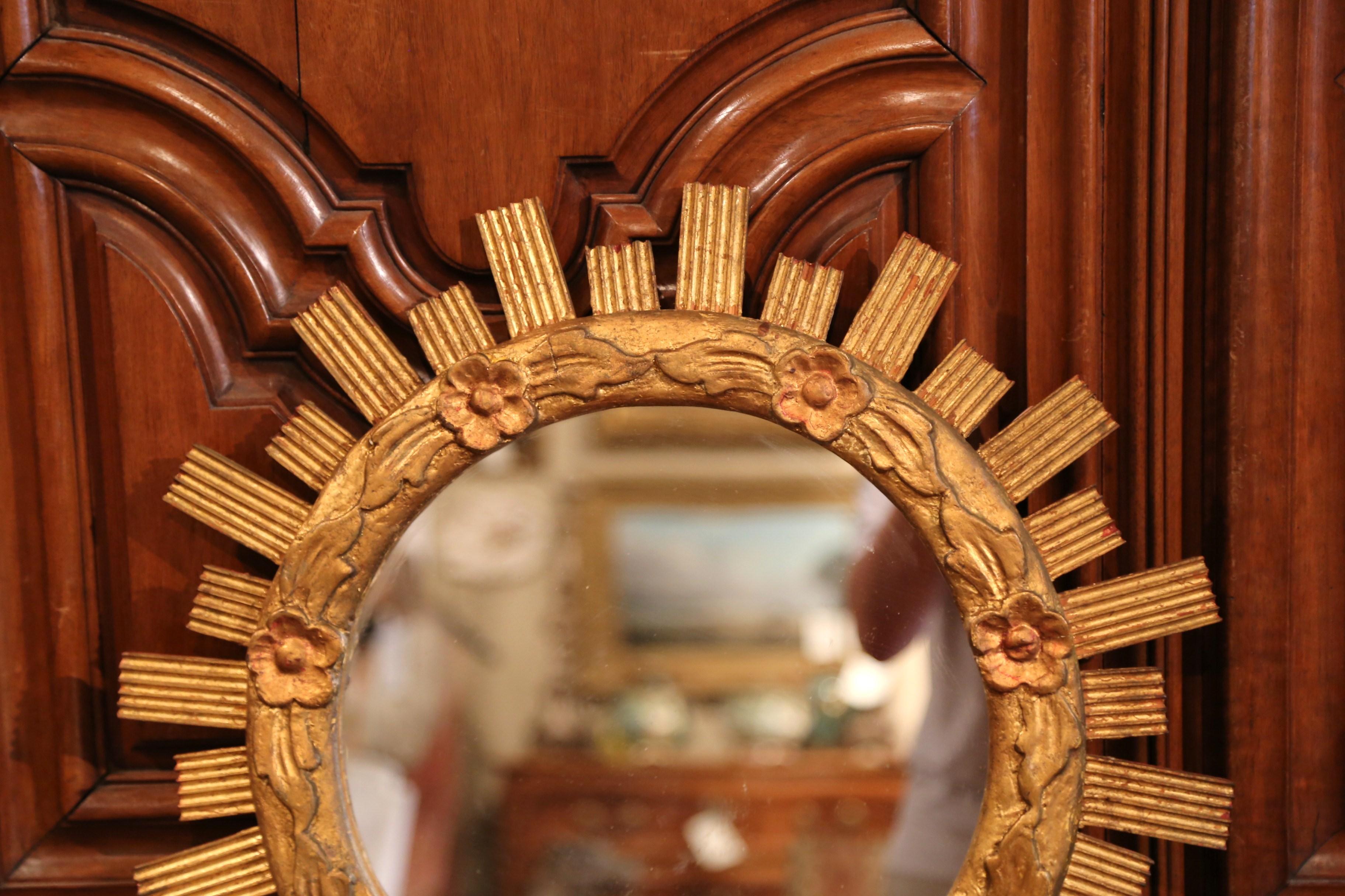 Create a focal point in any room with this elegant hand carved sunburst mirror. Crafted in France, circa 1950, and round in shape, the mid-century piece is decorated with intricate floral and leaf decor throughout and resembles the shape of a