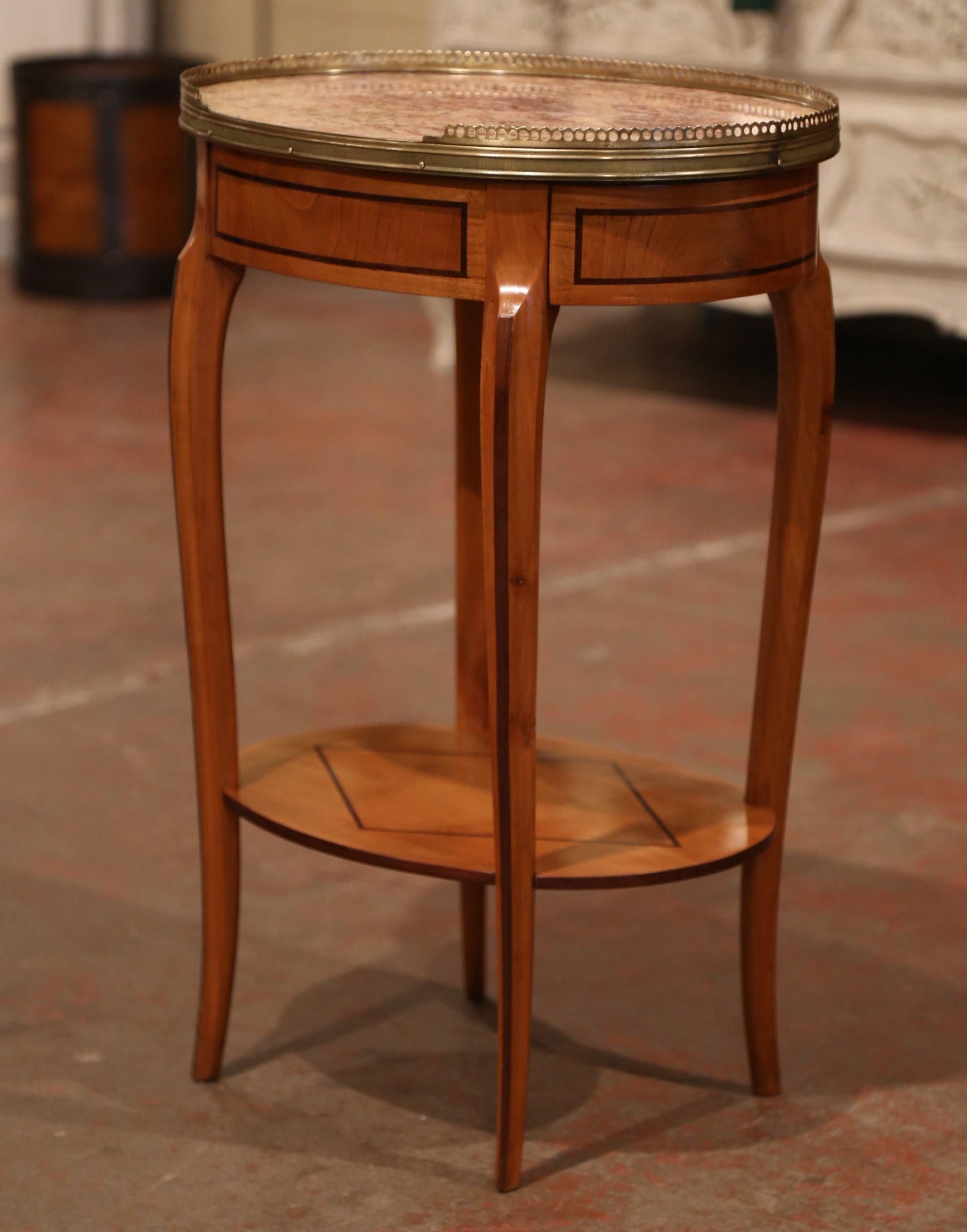 Crafted in France circa 1960 and made of cherrywood, the oval table sits on four cabriole legs over a lower tear. The table features detailed marquetry work around the apron, and is further embellished with a frieze drawer at one end. The luxurious