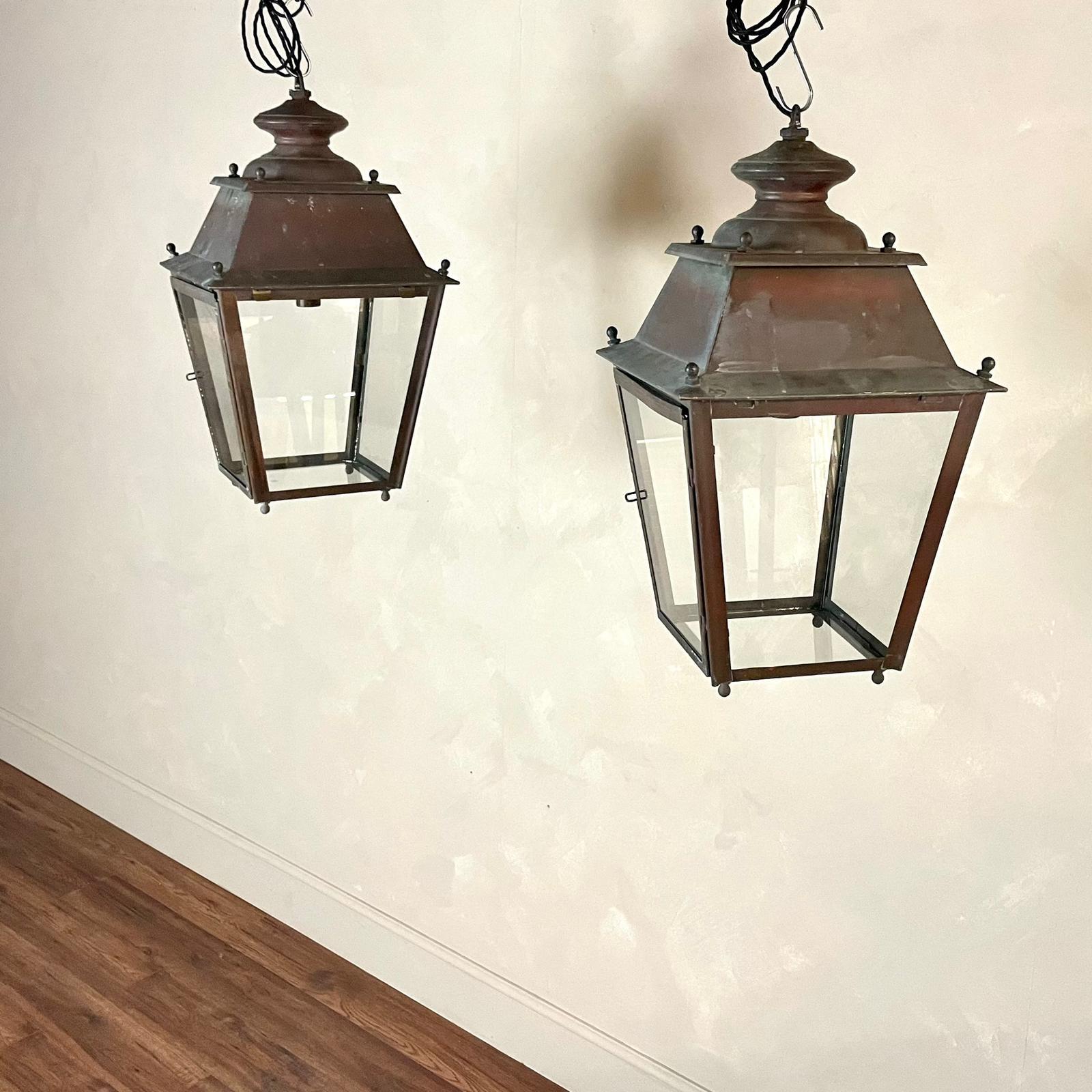 A superb pair of 20th century copper lanterns featuring a rounded spire to top surrounded by four ball finials set on an outward roof. 
Newly glazed panels that taper inward, and glazed on the base ending with four ball finials. One of the panels